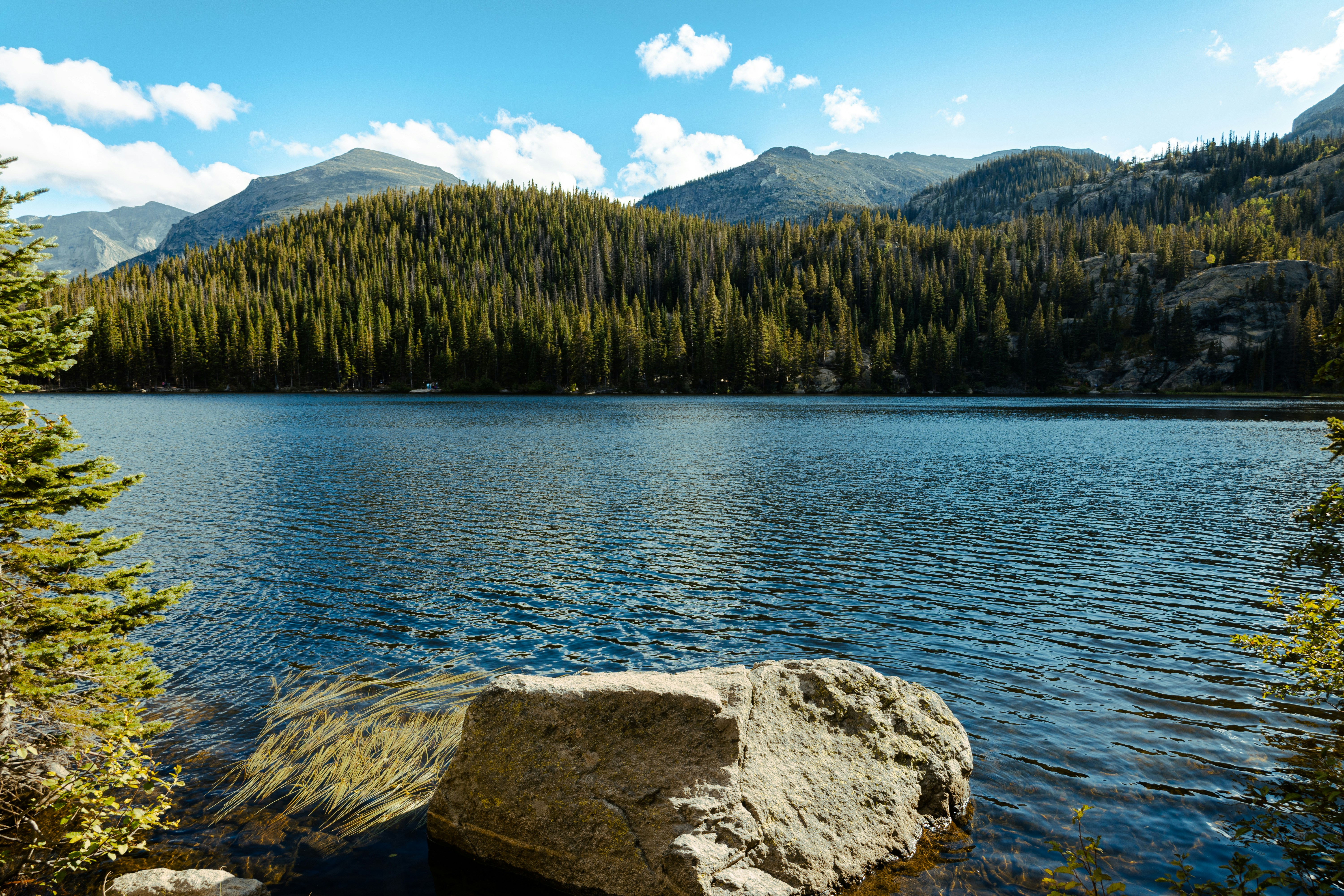 A large rock sitting on the shore of a lake