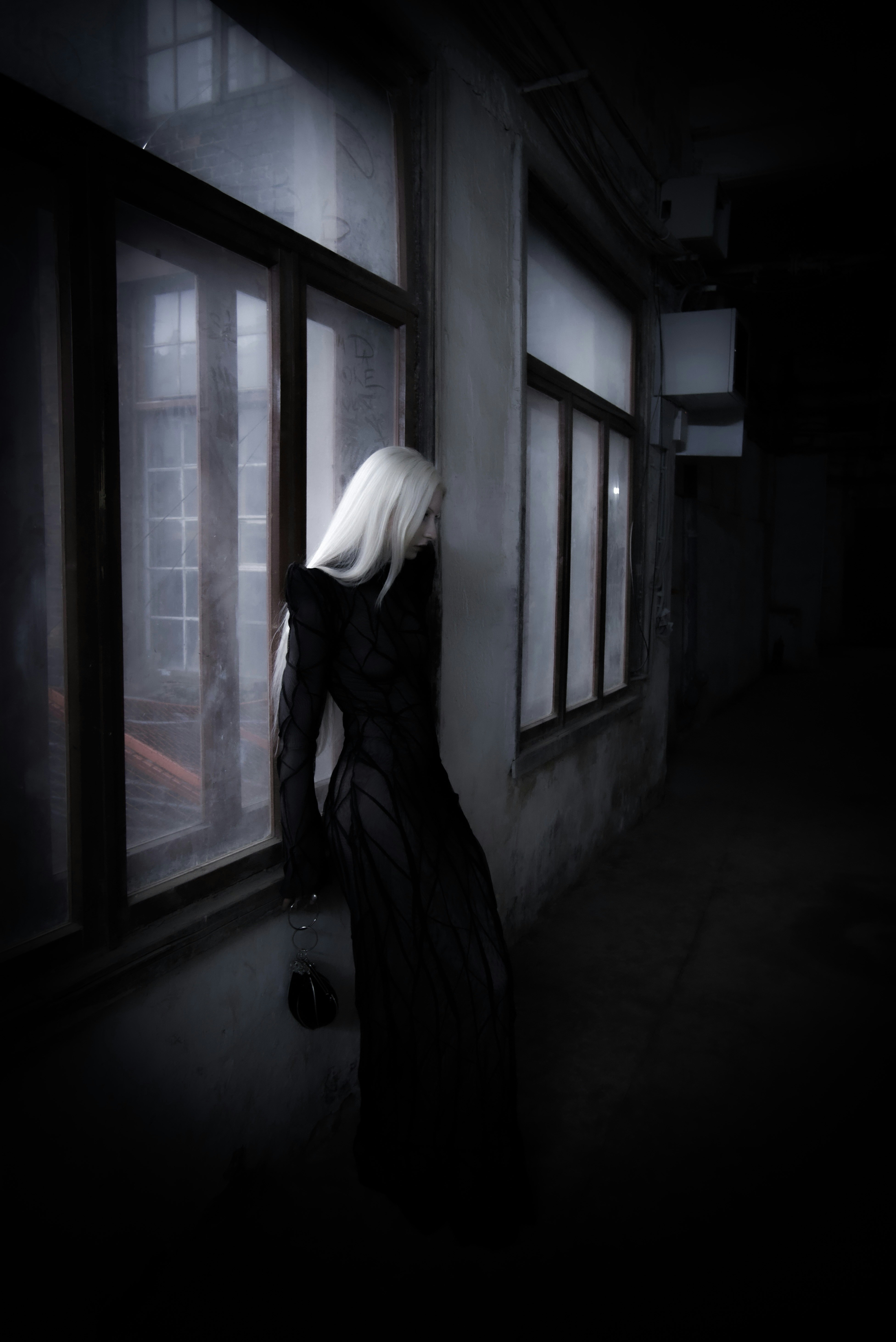 A woman standing in front of a window in a dark room