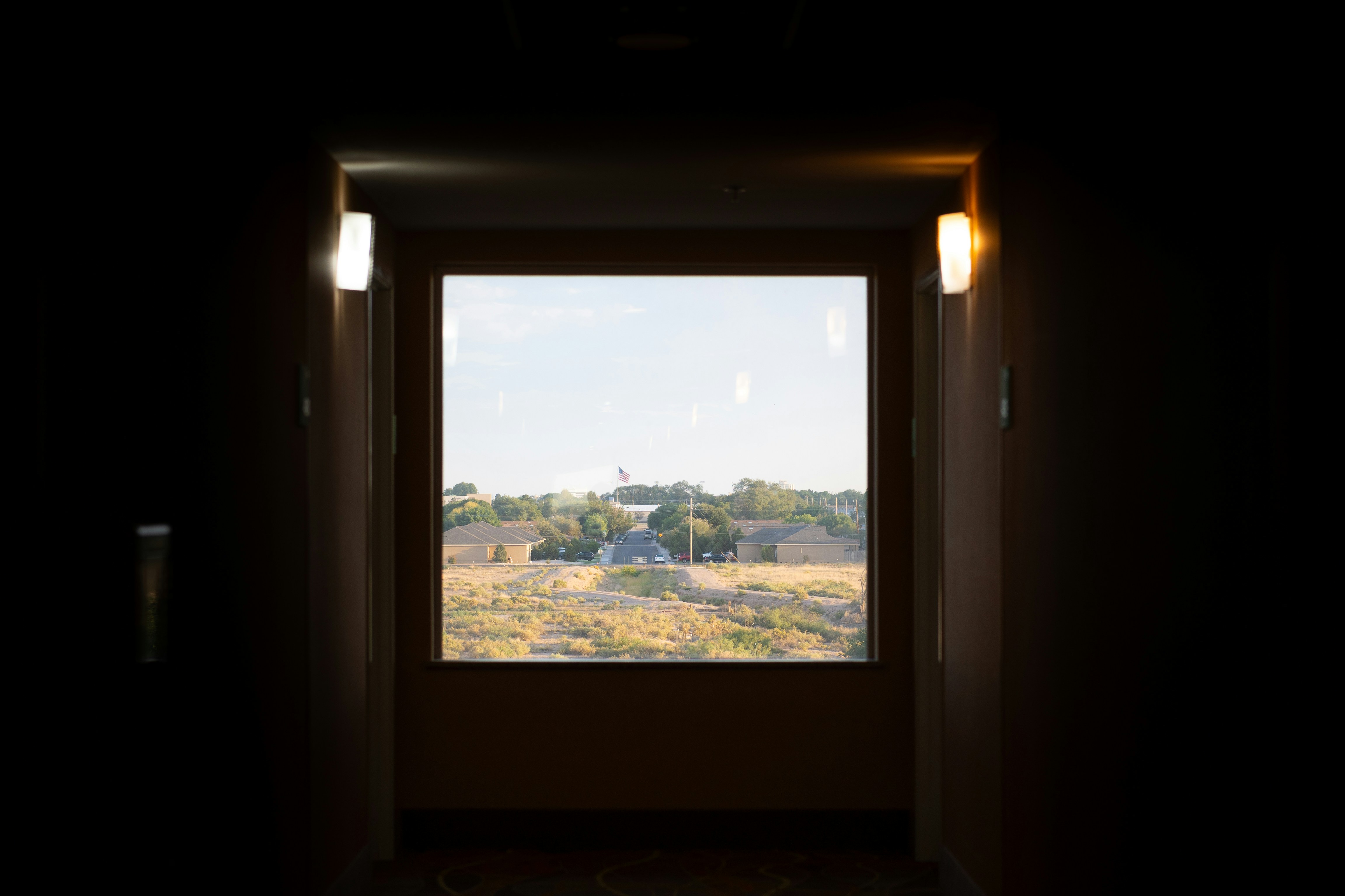 An open window in a dark room with a view of a field