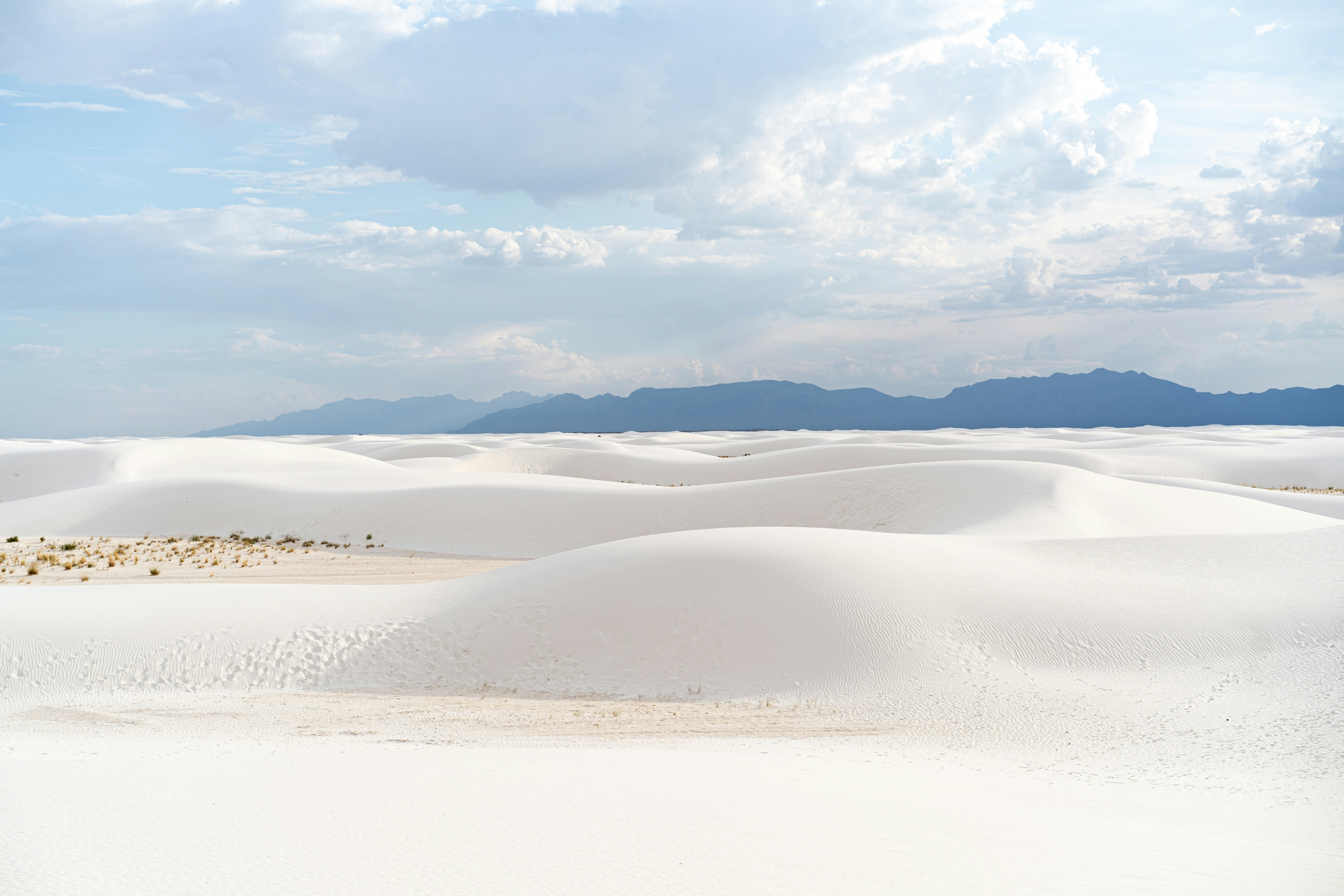A large expanse of white sand with mountains in the distance