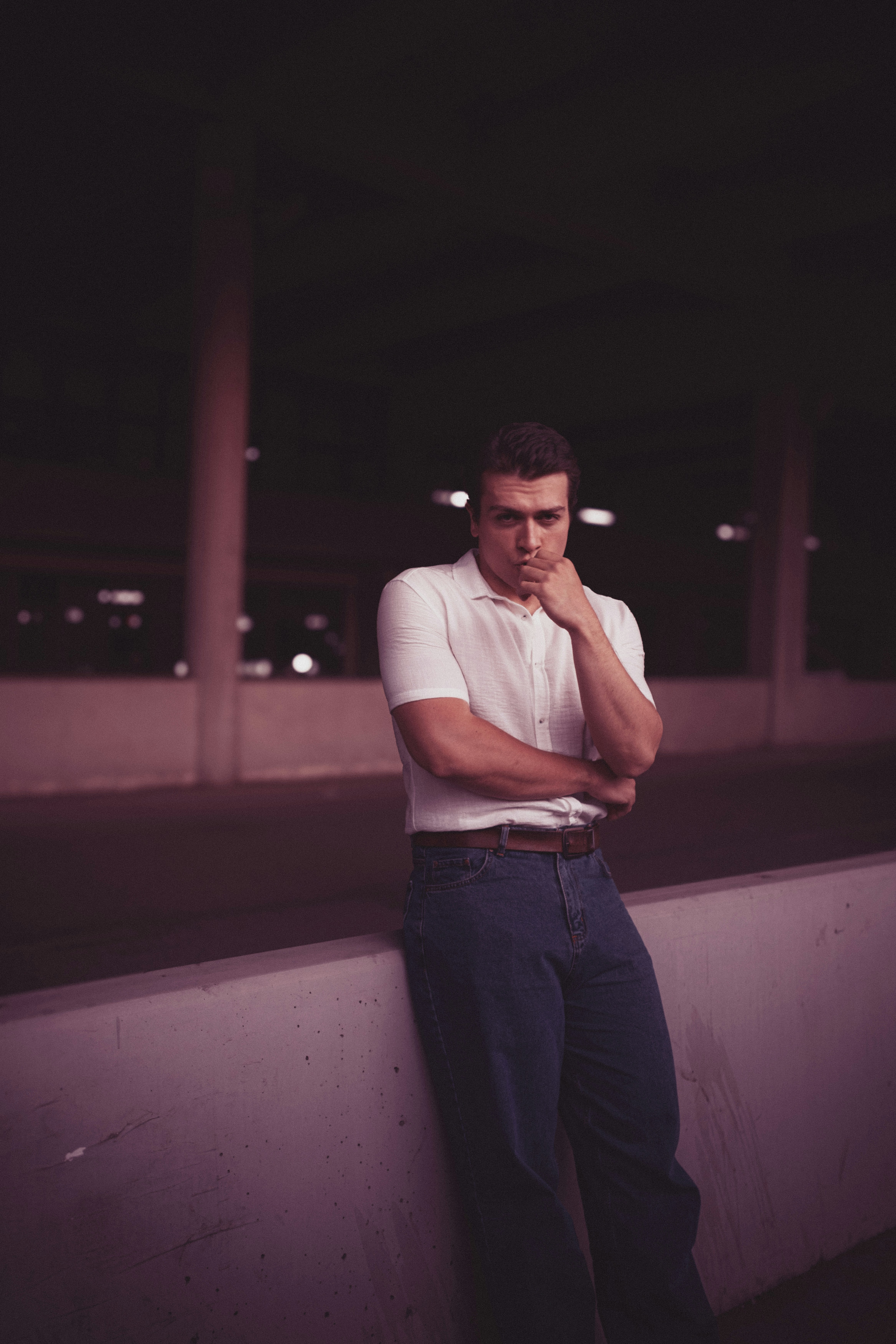 A man leaning against a wall with his hand on his chin
