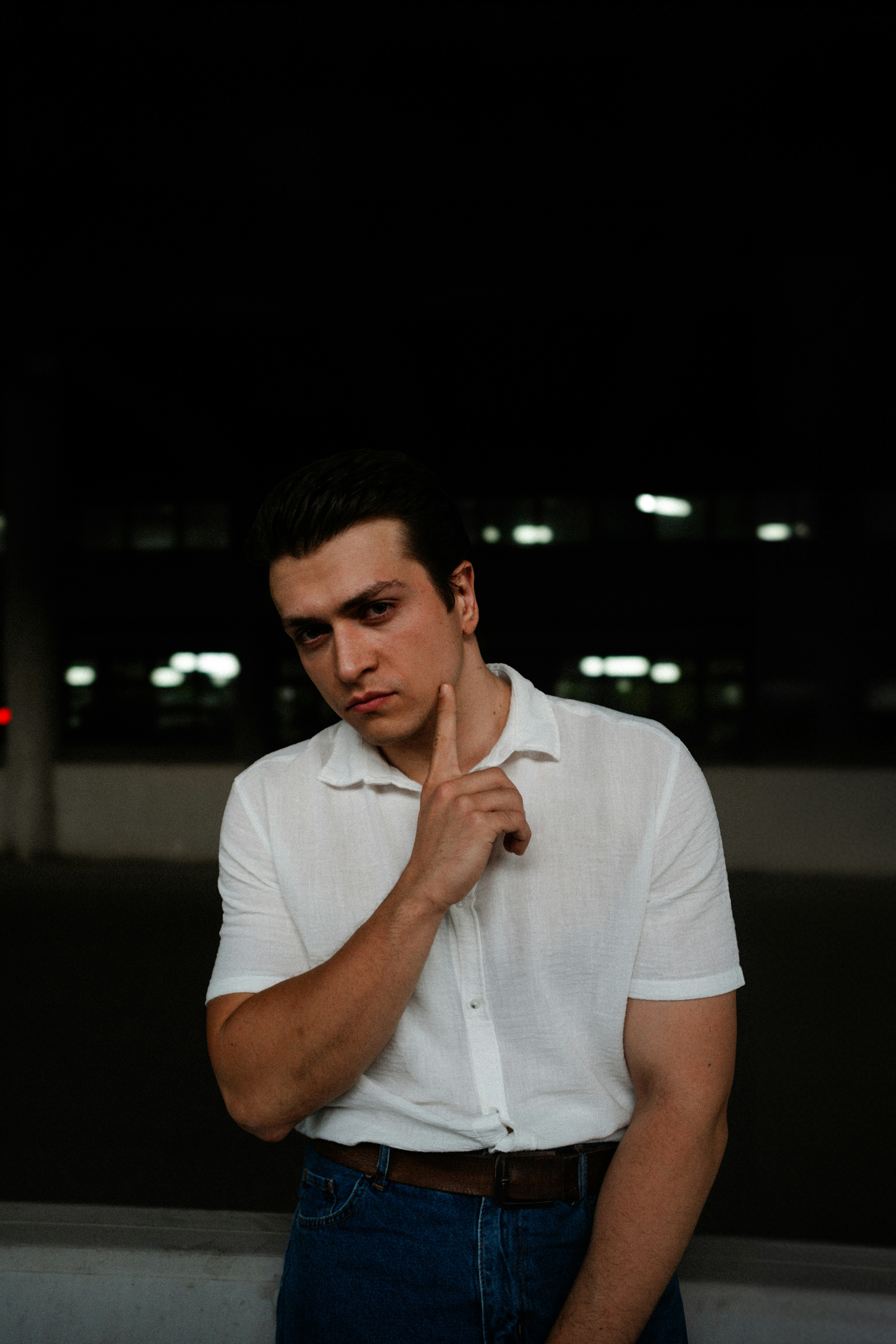 A man in a white shirt is standing in the dark