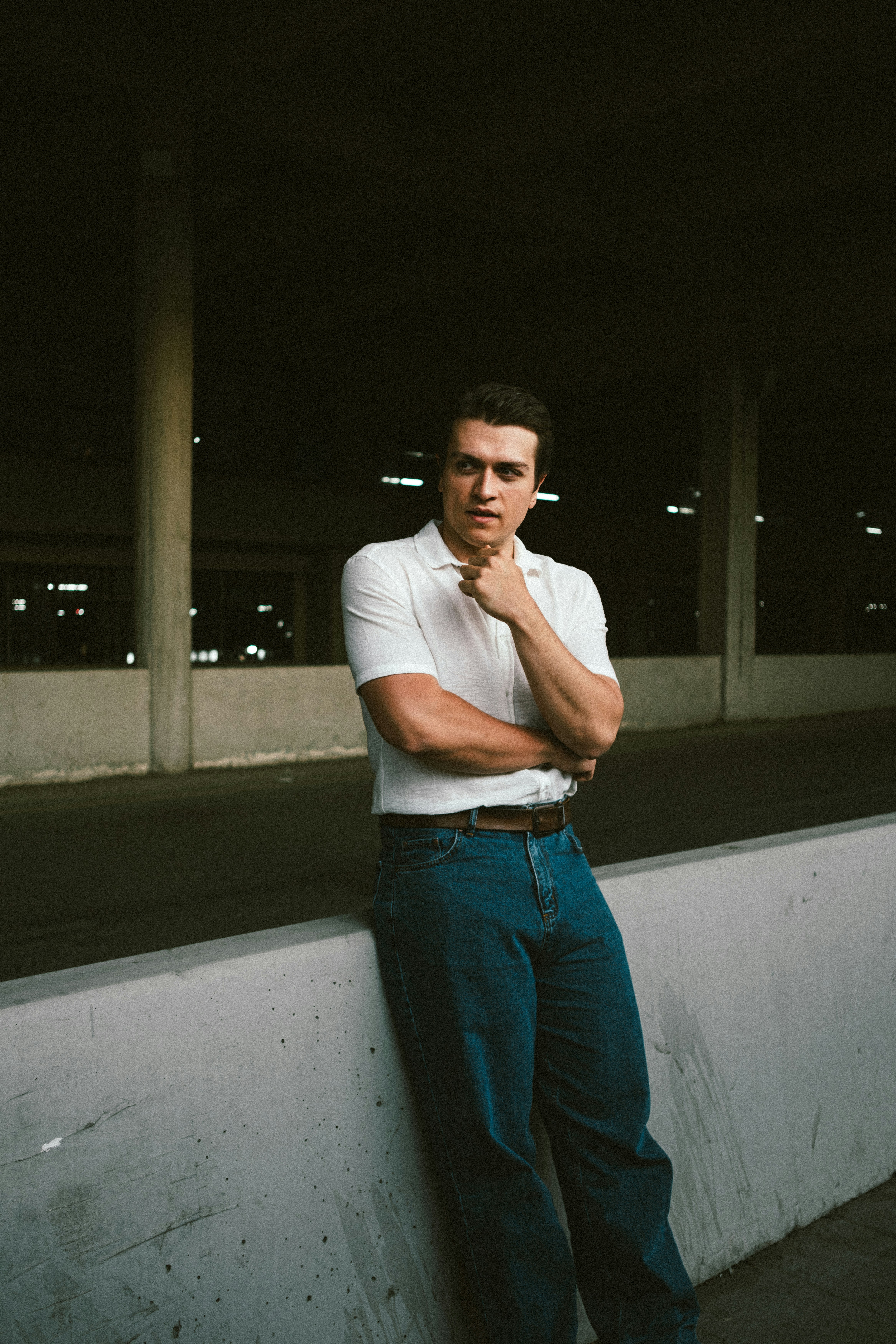 A man leaning against a wall with his hand on his chin