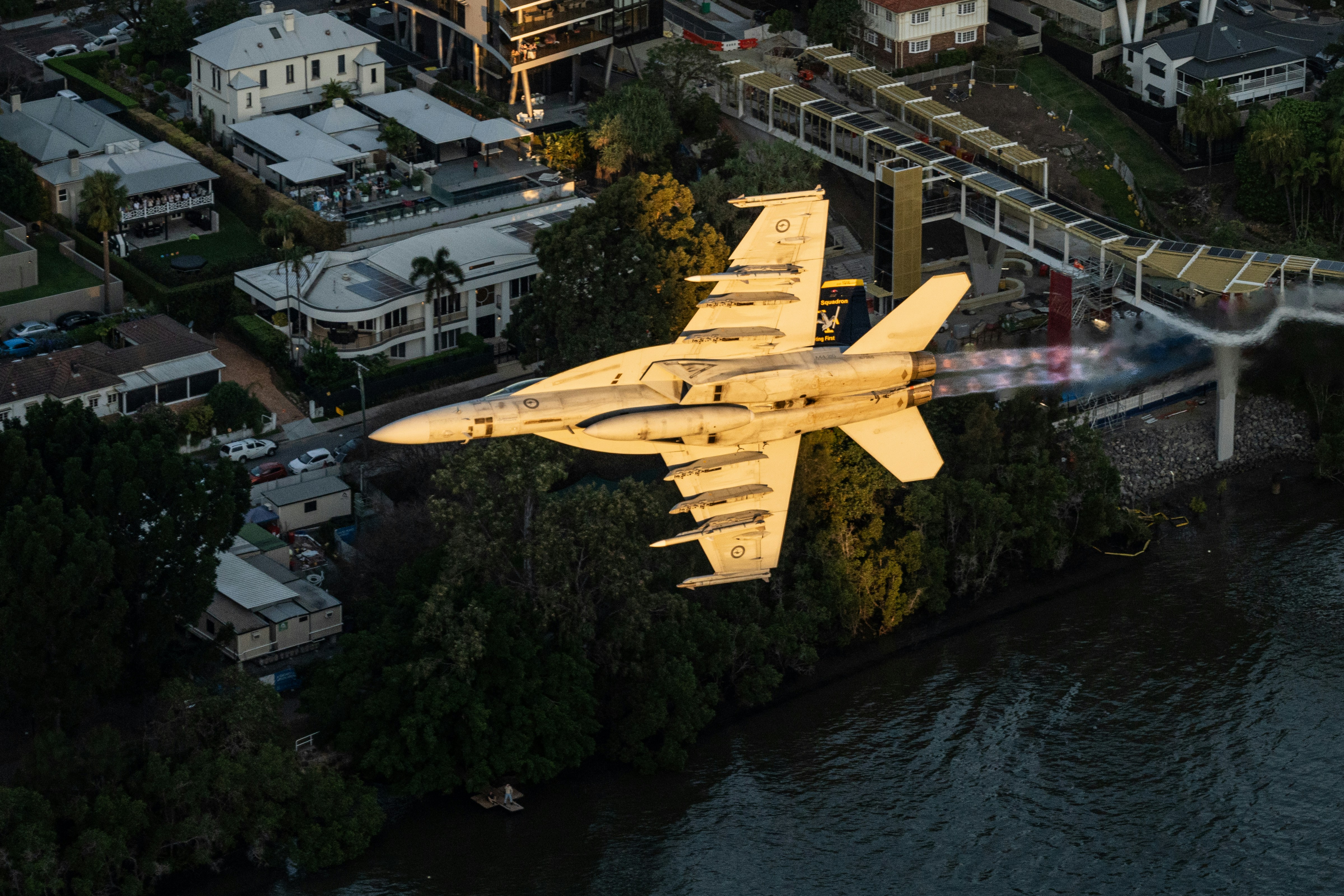 A large jet flying over a city next to a river