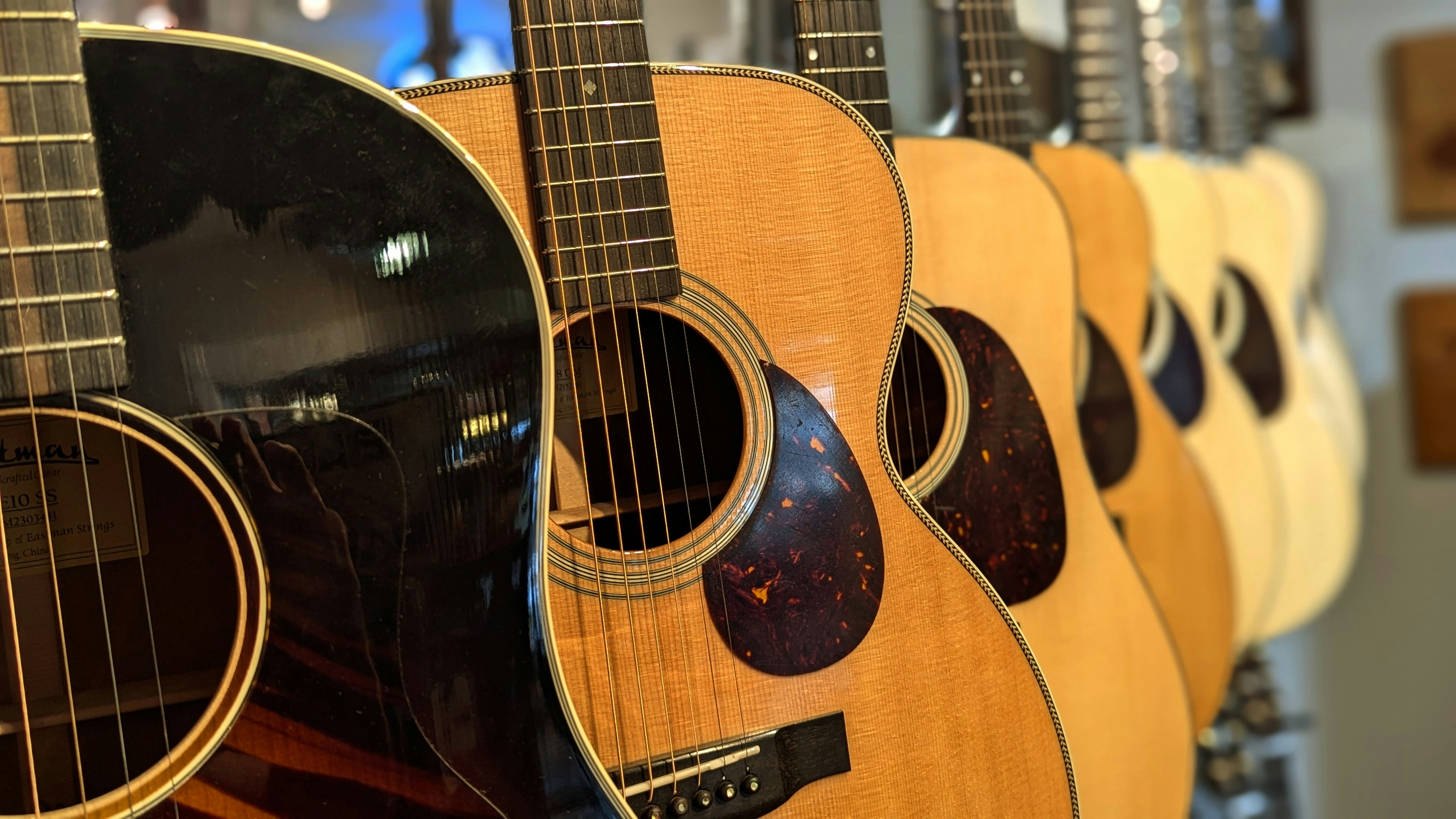 A row of acoustic guitars hanging on a wall