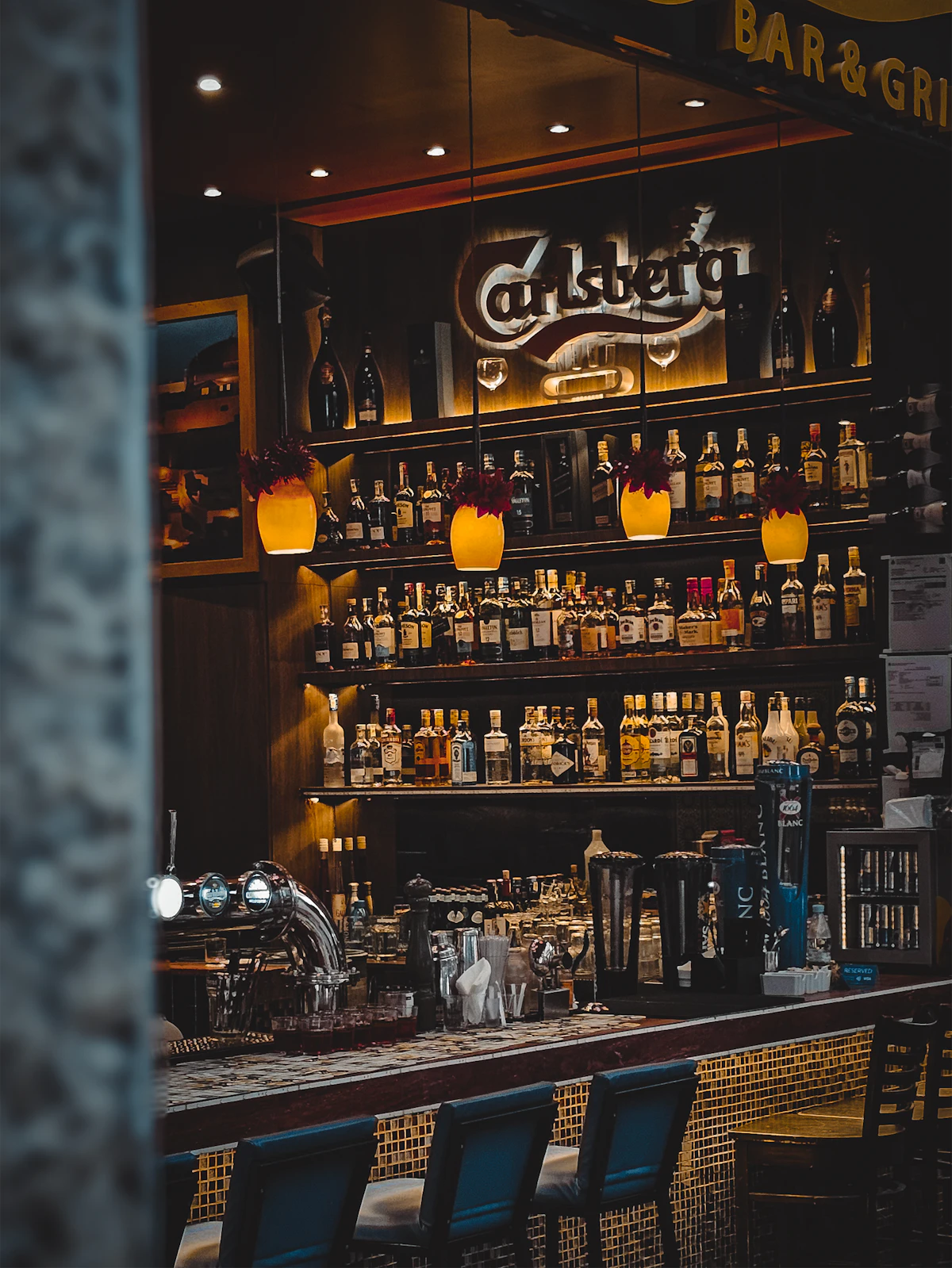 A back bar stacked with bottles, glass and labels catching the low amber light of a listening room.