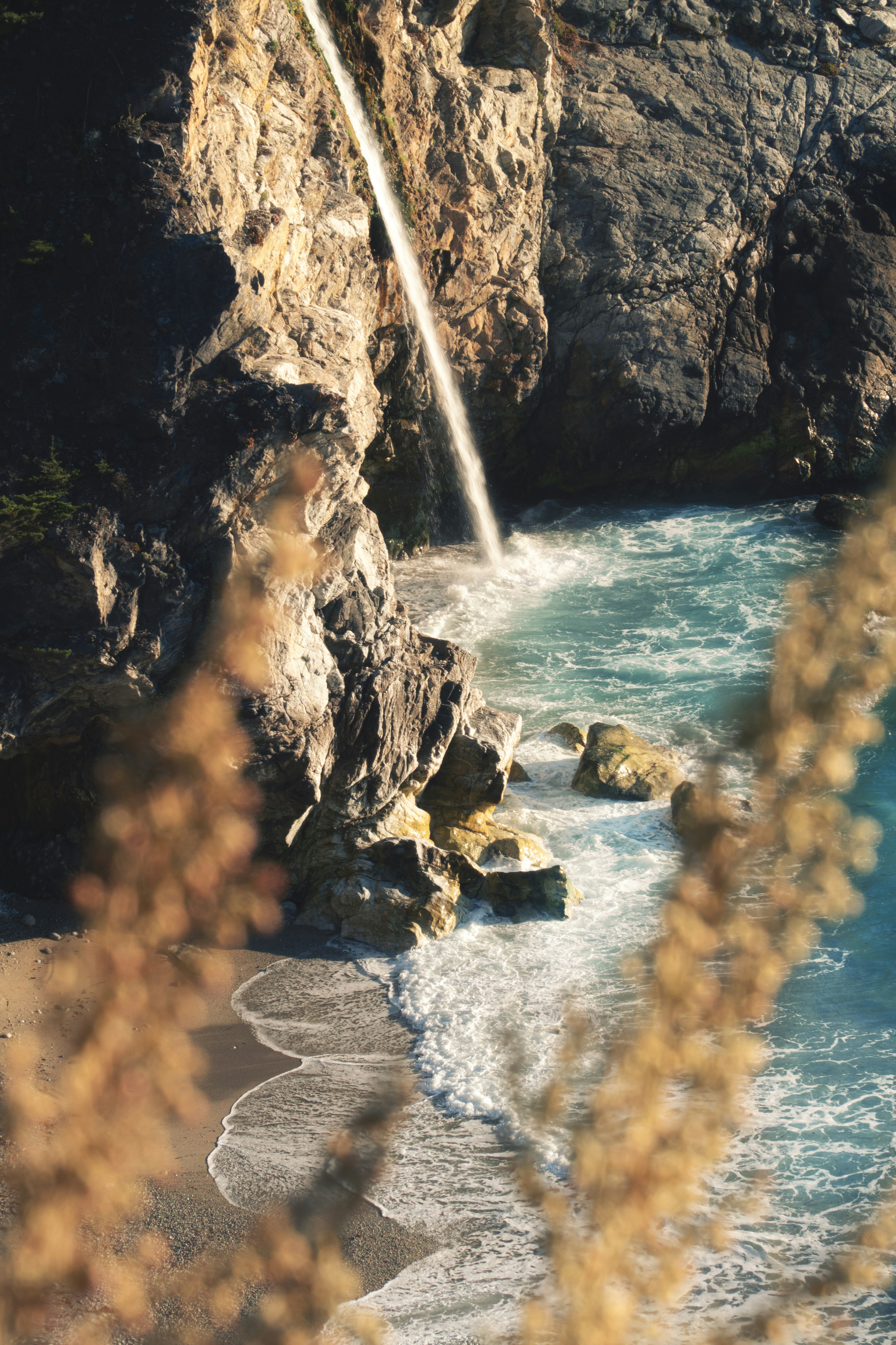 A view of a beach with a waterfall coming out of the rocks photo – Free ...