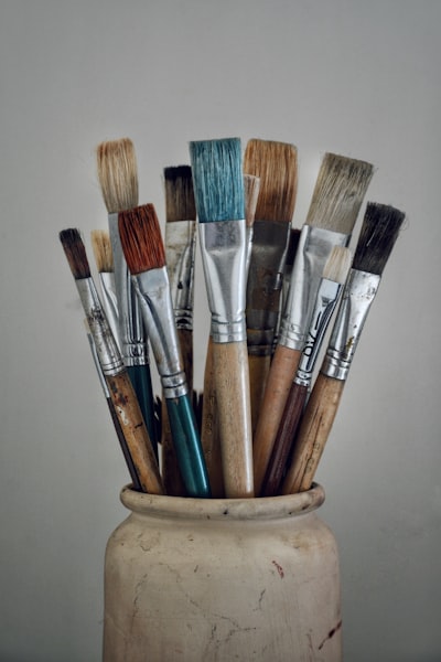 Paint brushes arranged in a vase on workspace