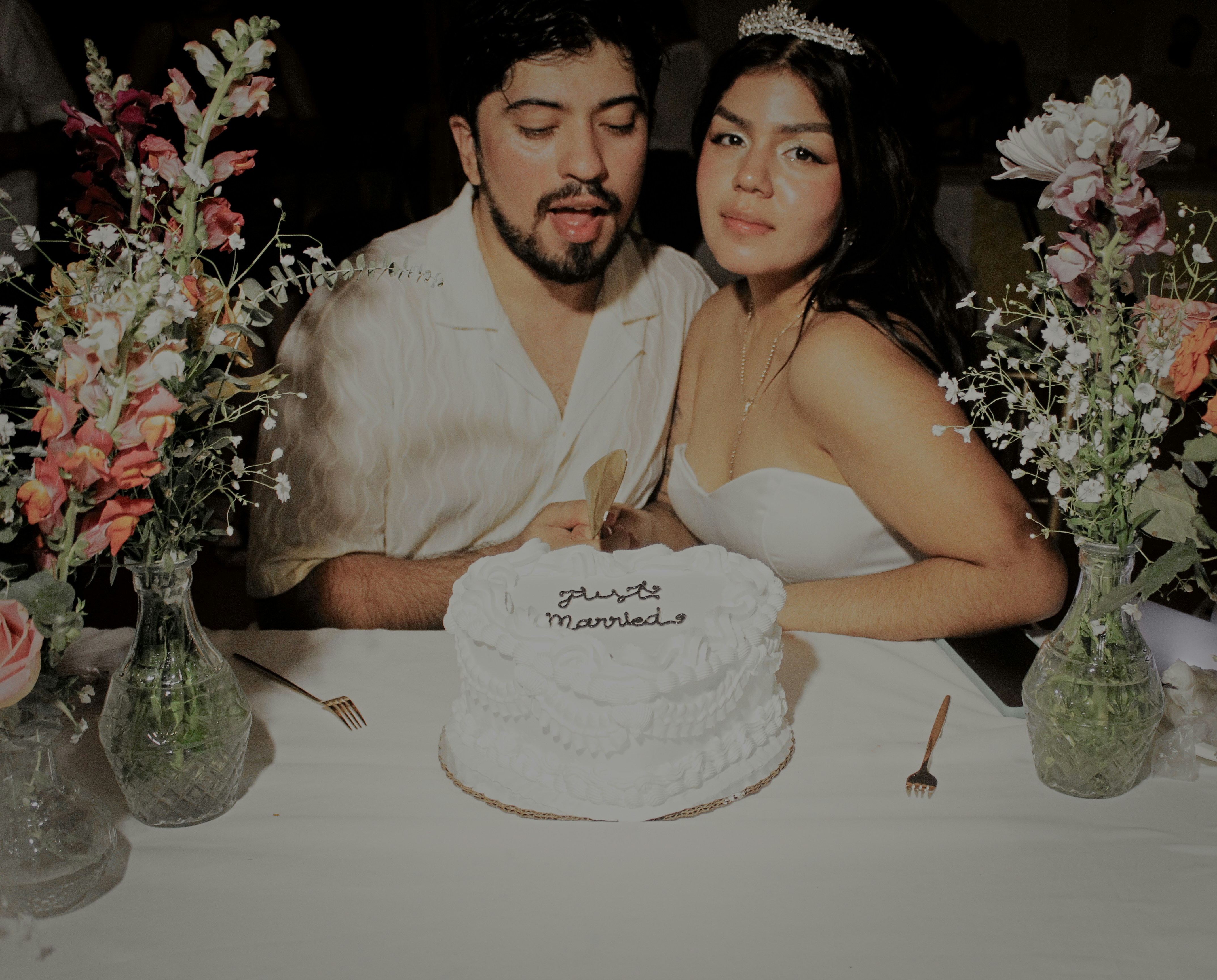 Bride and groom cutting wedding cake surrounded by guests