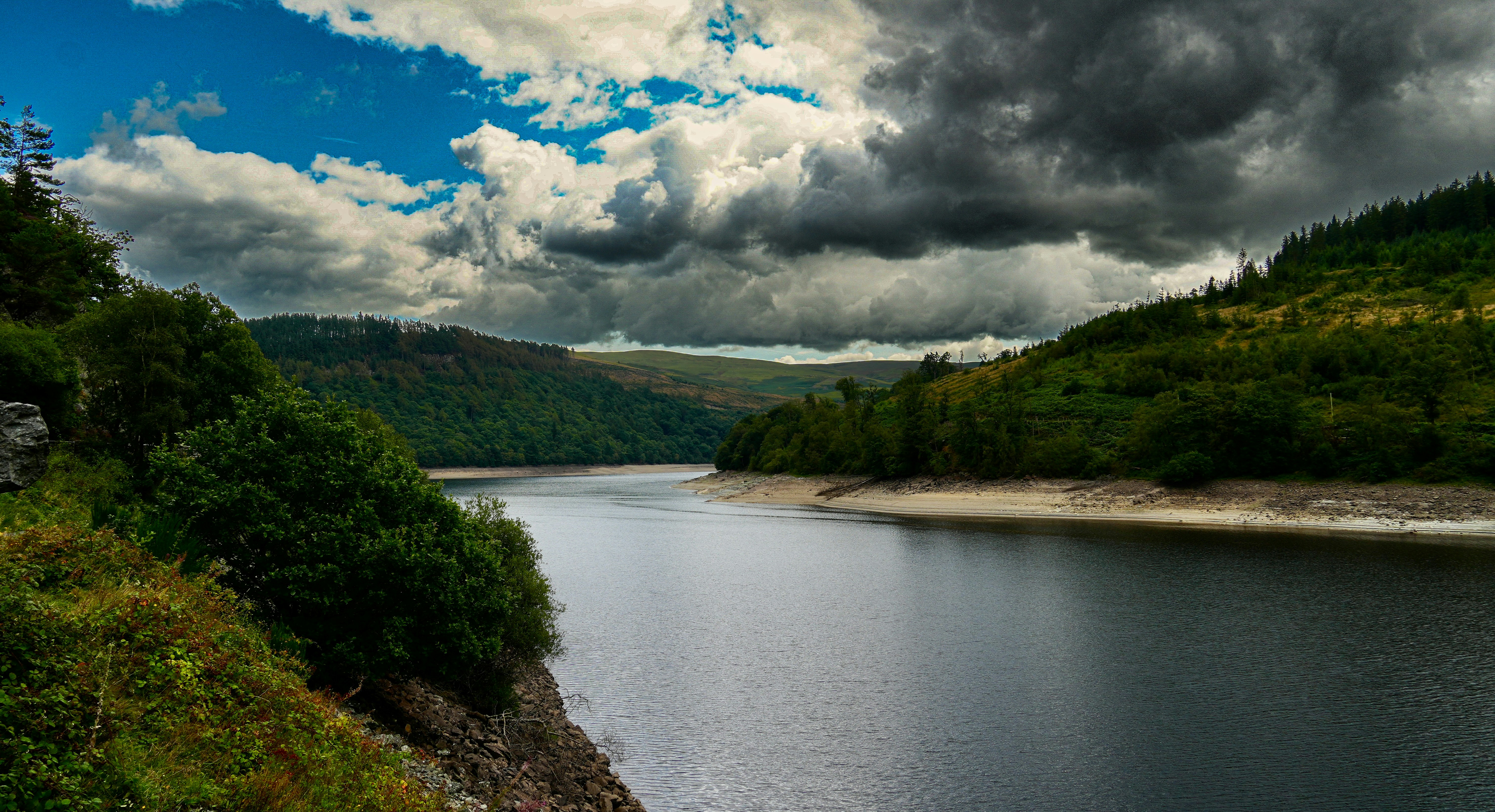 A large body of water surrounded by a lush green hillside