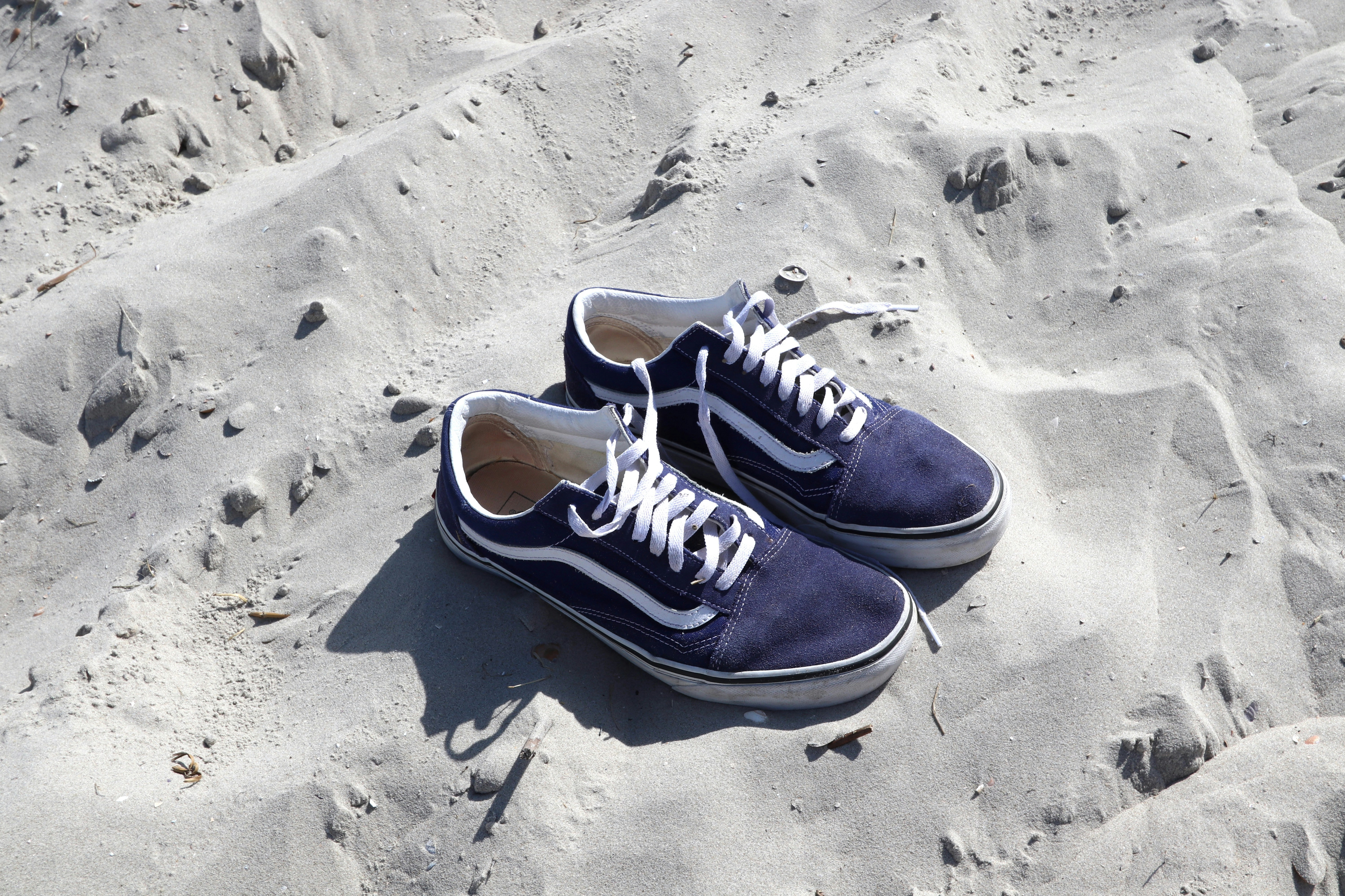 A pair of blue vans sitting on top of a sandy beach