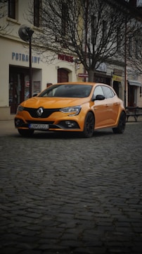 An orange car parked on a cobblestone street