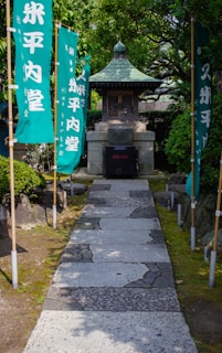 A walkway with flags and a shrine in the background