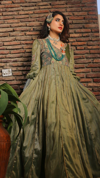 A woman in a green dress standing next to a brick wall