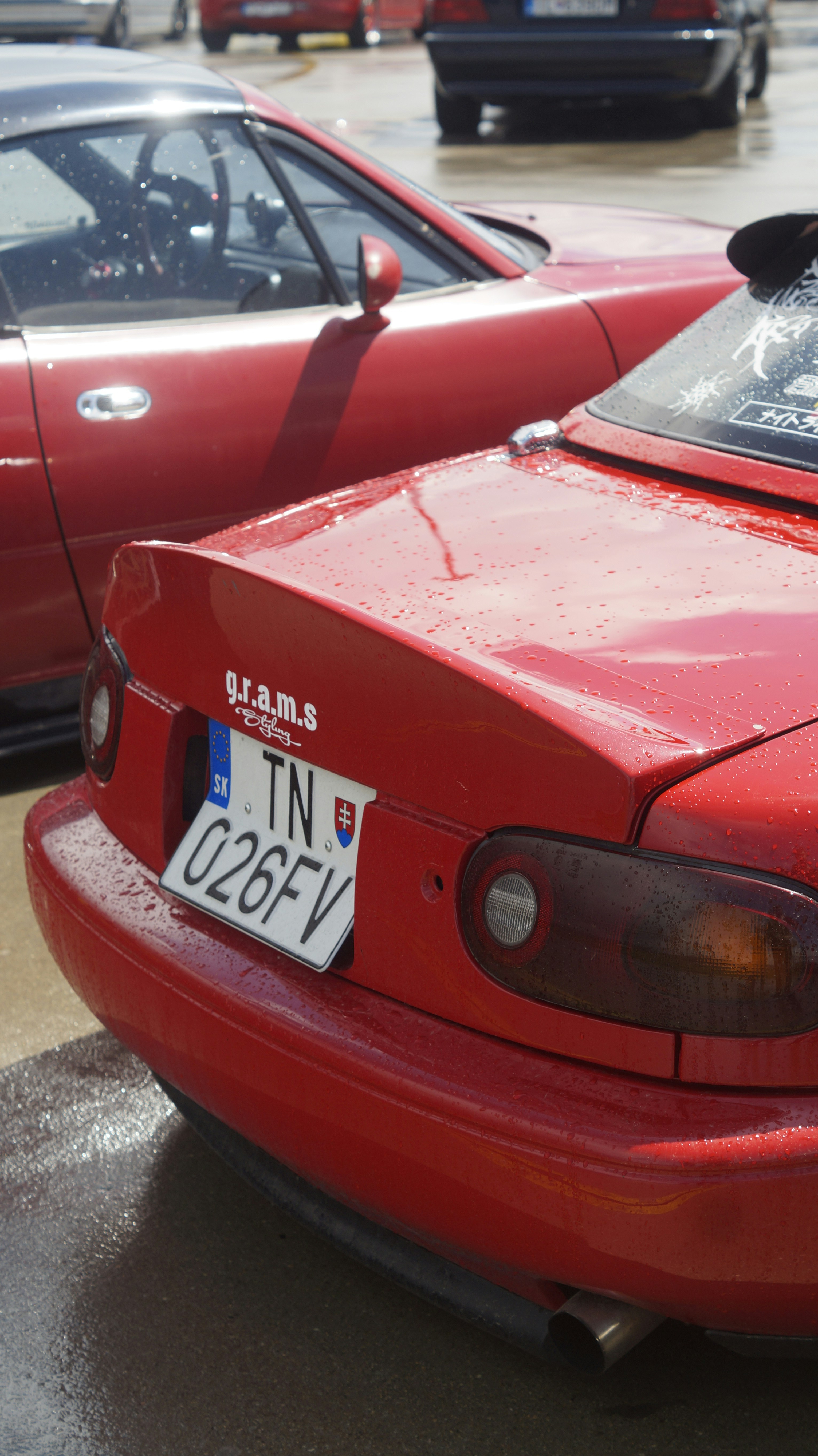 A red car parked in a parking lot next to other cars