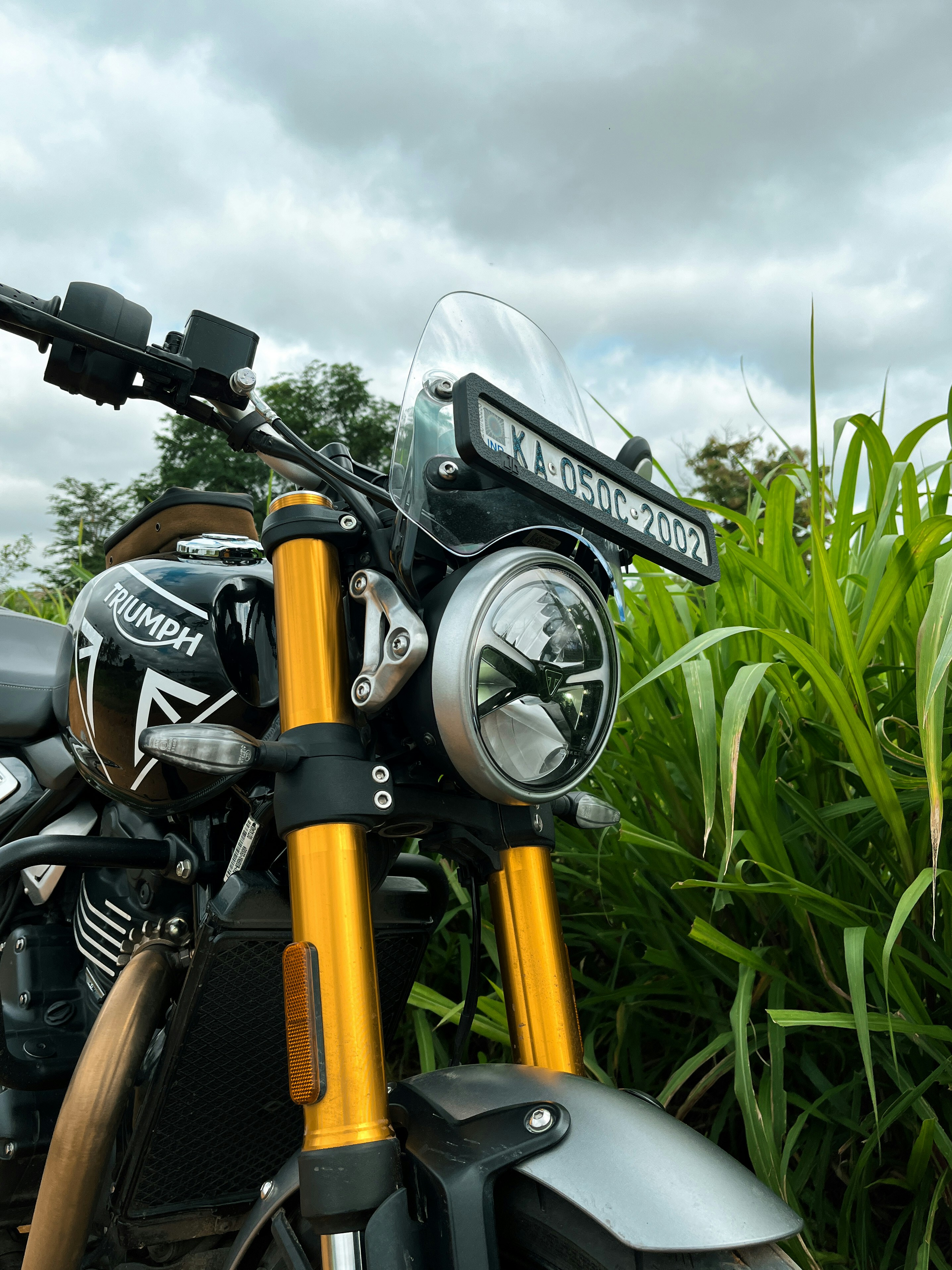 A motorcycle parked in front of a lush green field