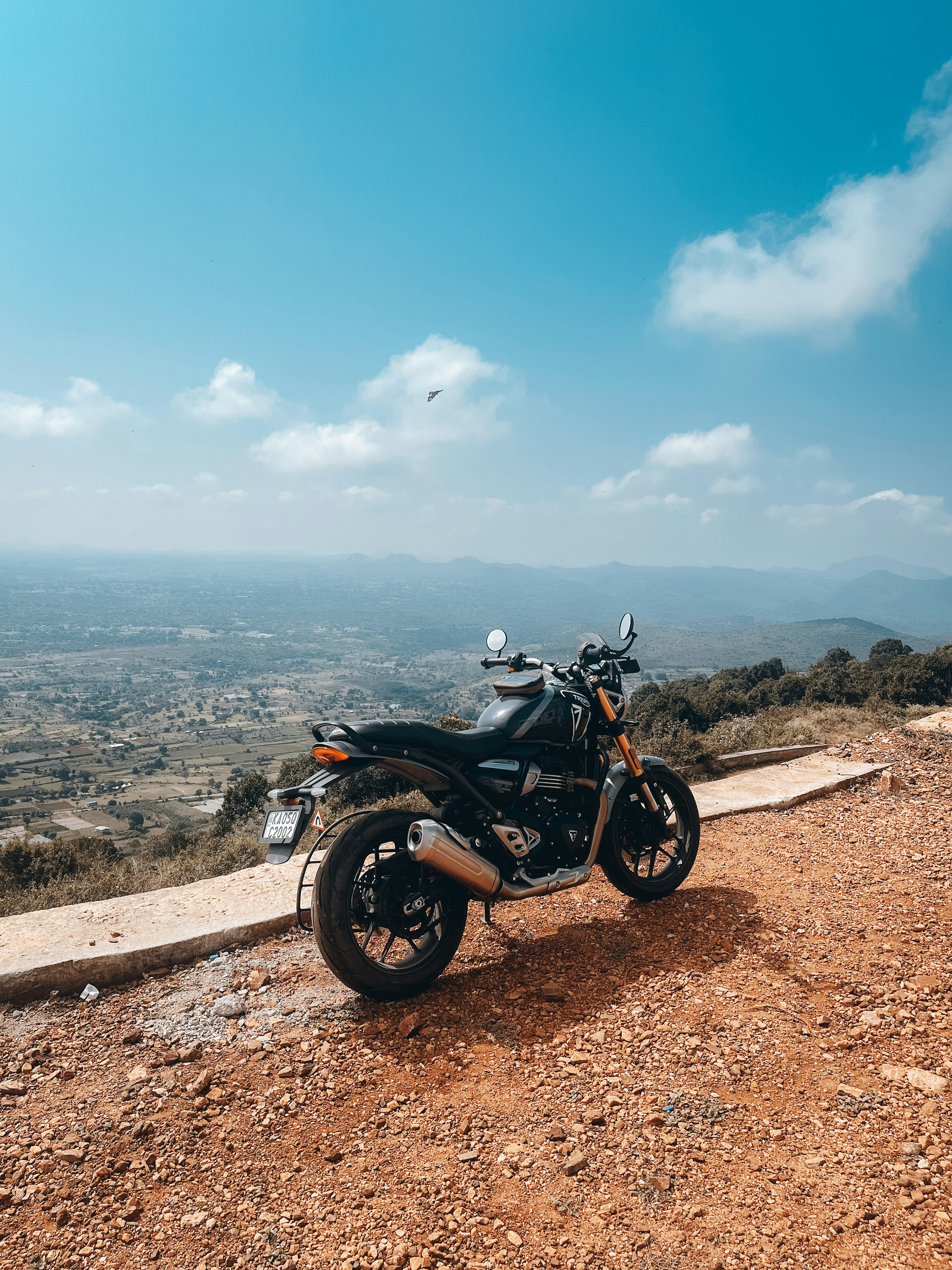 Motorcycle parked at cliff edge overlook, vast canyon below, dramatic sky with storm clouds forming