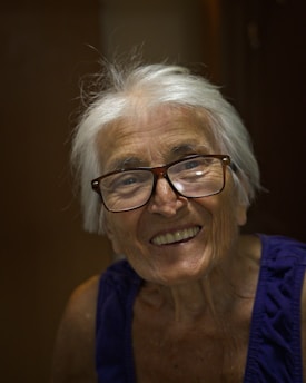 An older woman with glasses smiling at the camera