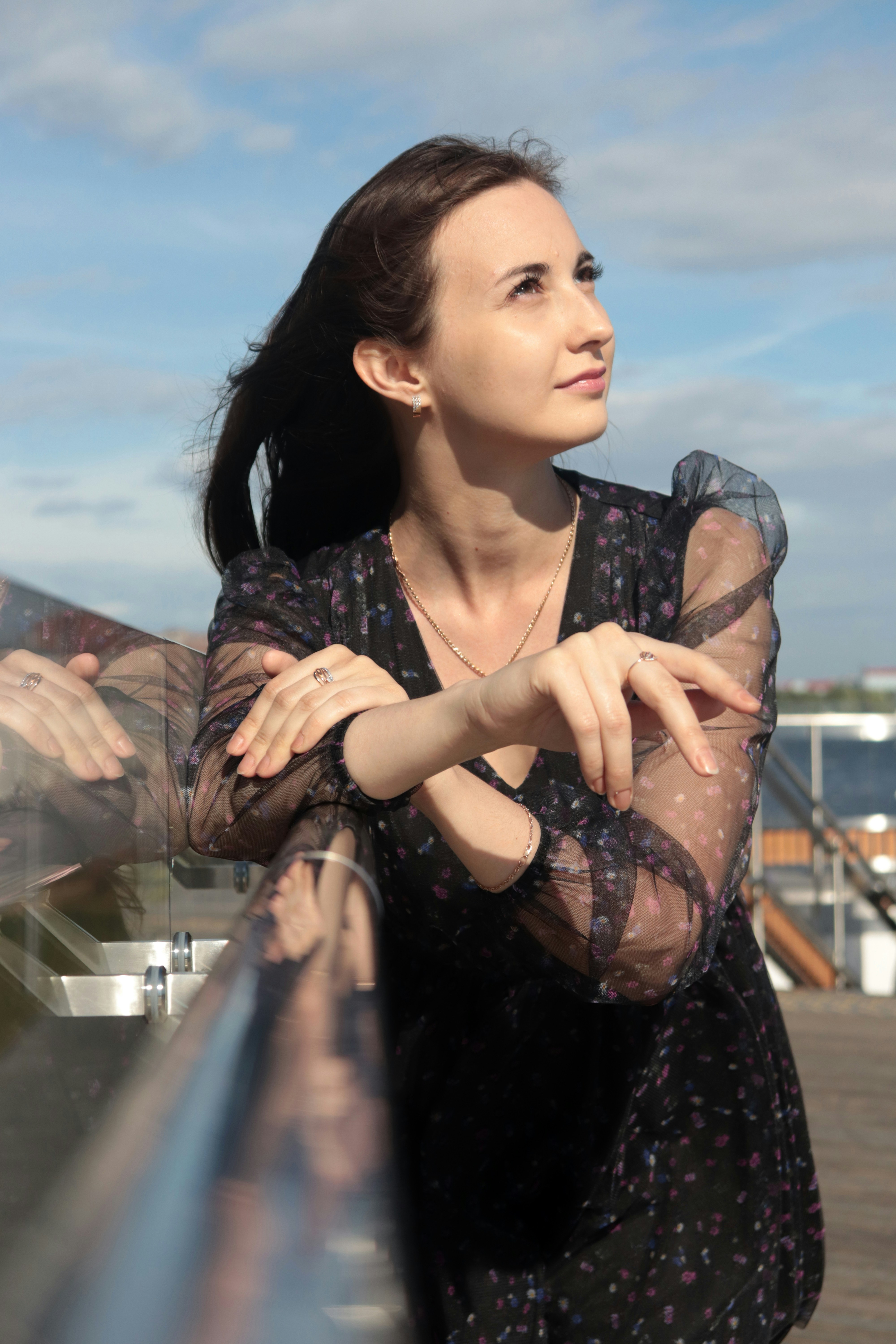 Una mujer apoyada en una barandilla con los brazos cruzados