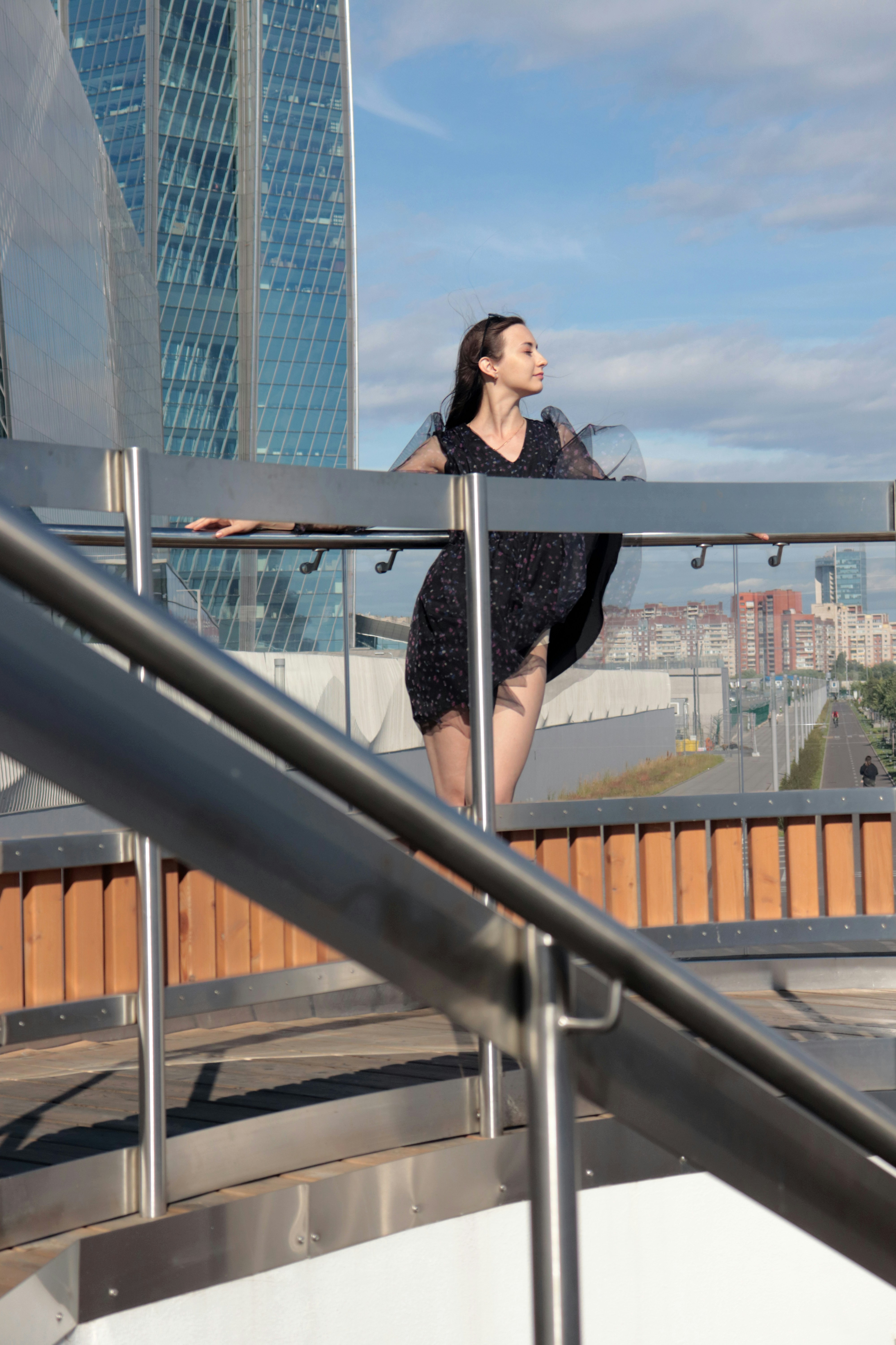 Una mujer con un vestido negro de pie sobre una barandilla