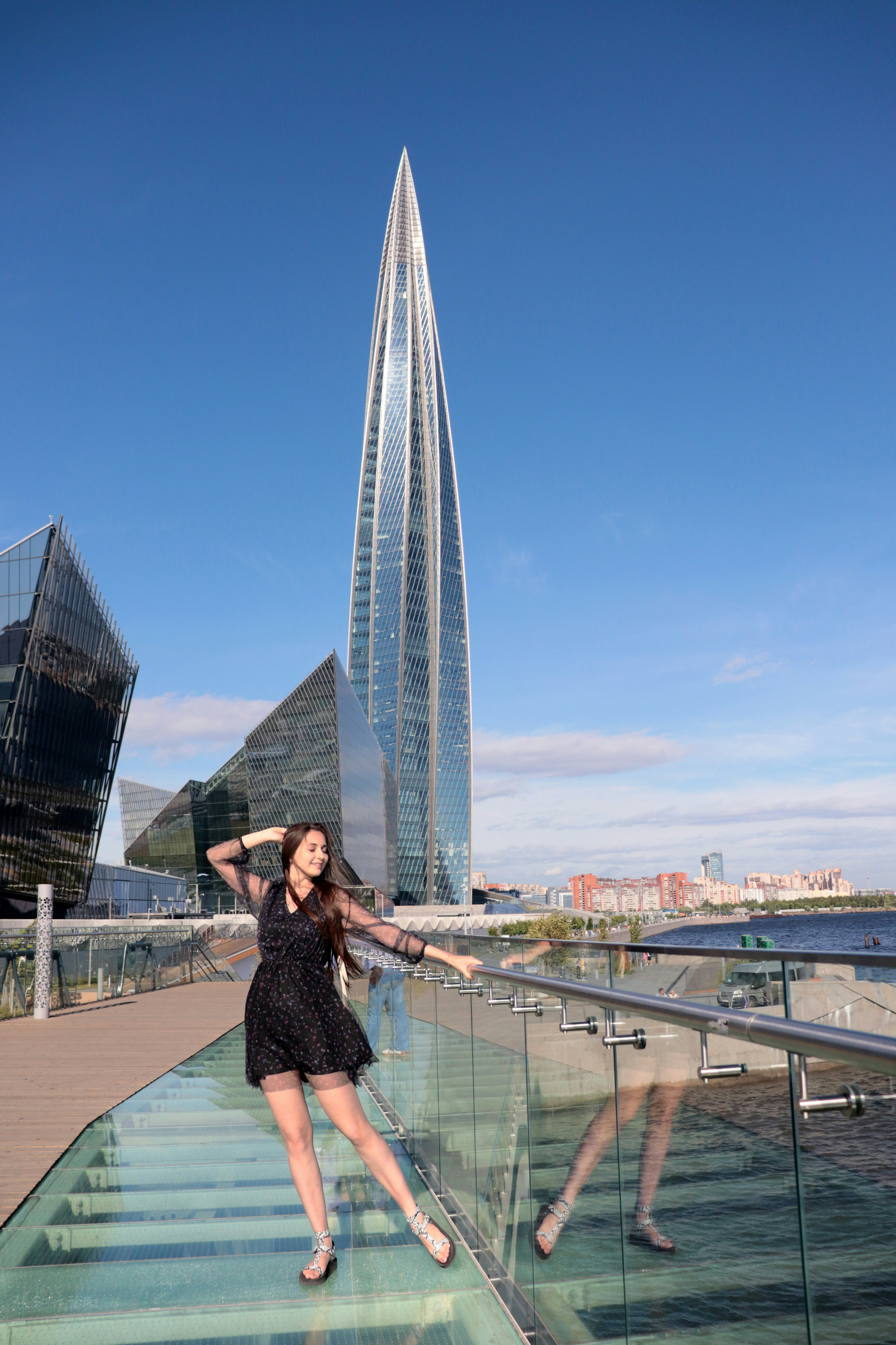 Una mujer de pie en una pasarela de cristal junto a un edificio alto