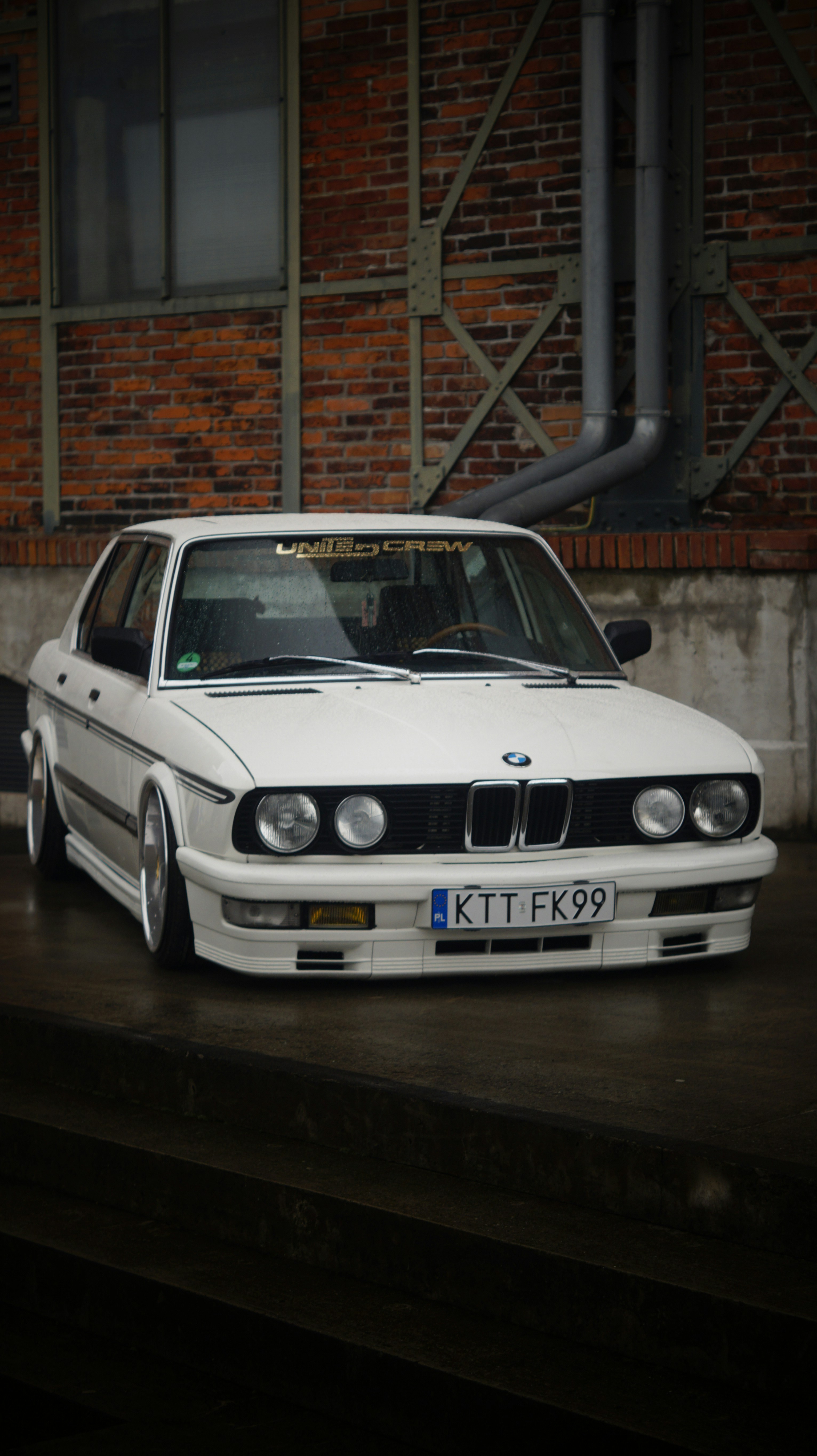 A white car parked in front of a brick building