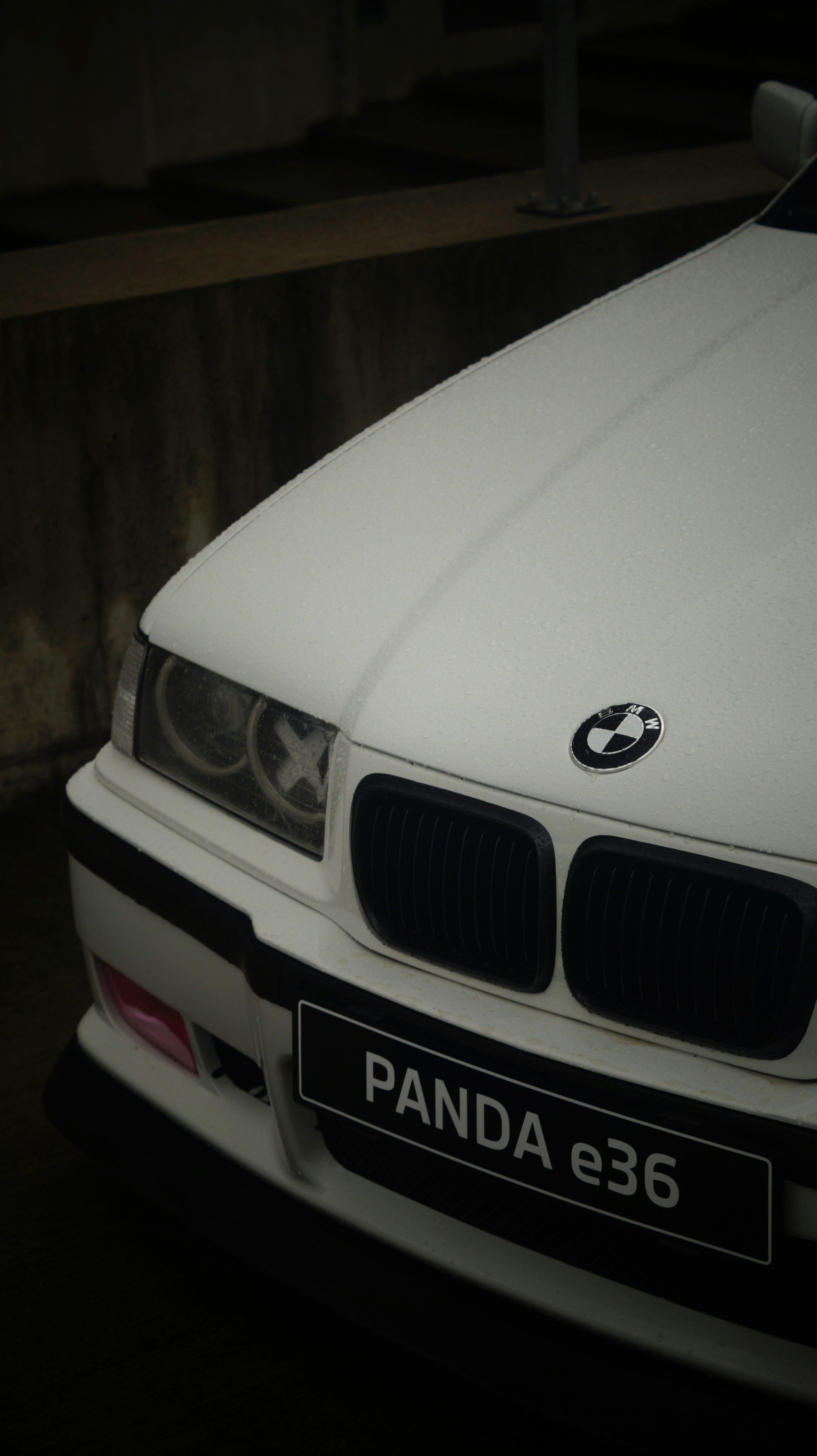 A white car parked next to a wall