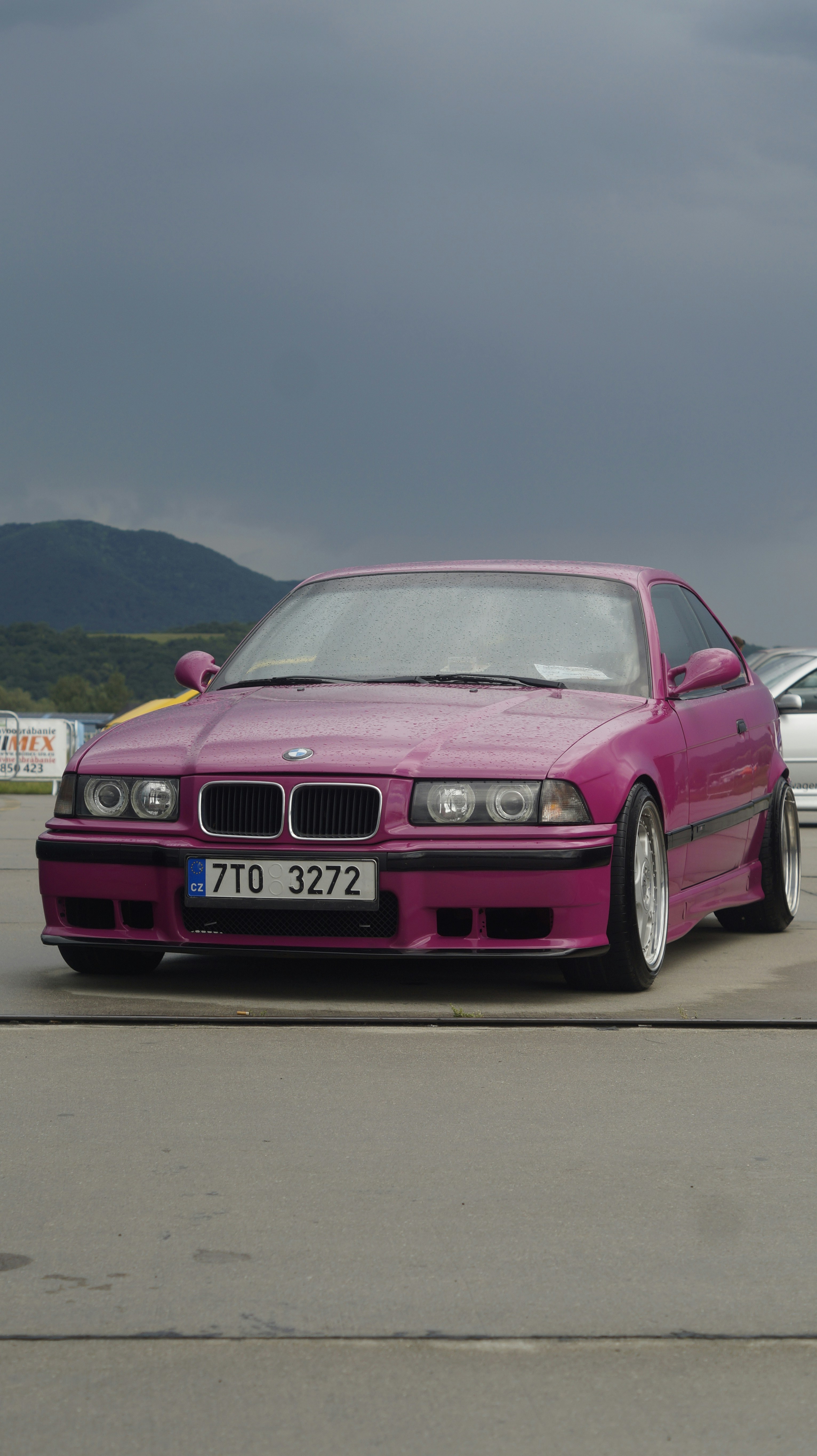 A pink car parked next to a white car