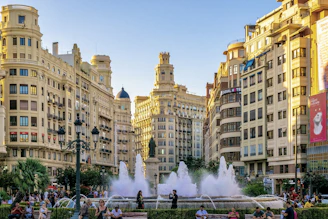 A group of people standing around a fountain in a city