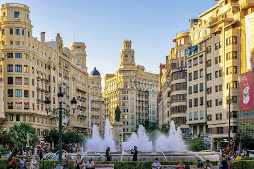 A group of people standing around a fountain in a city