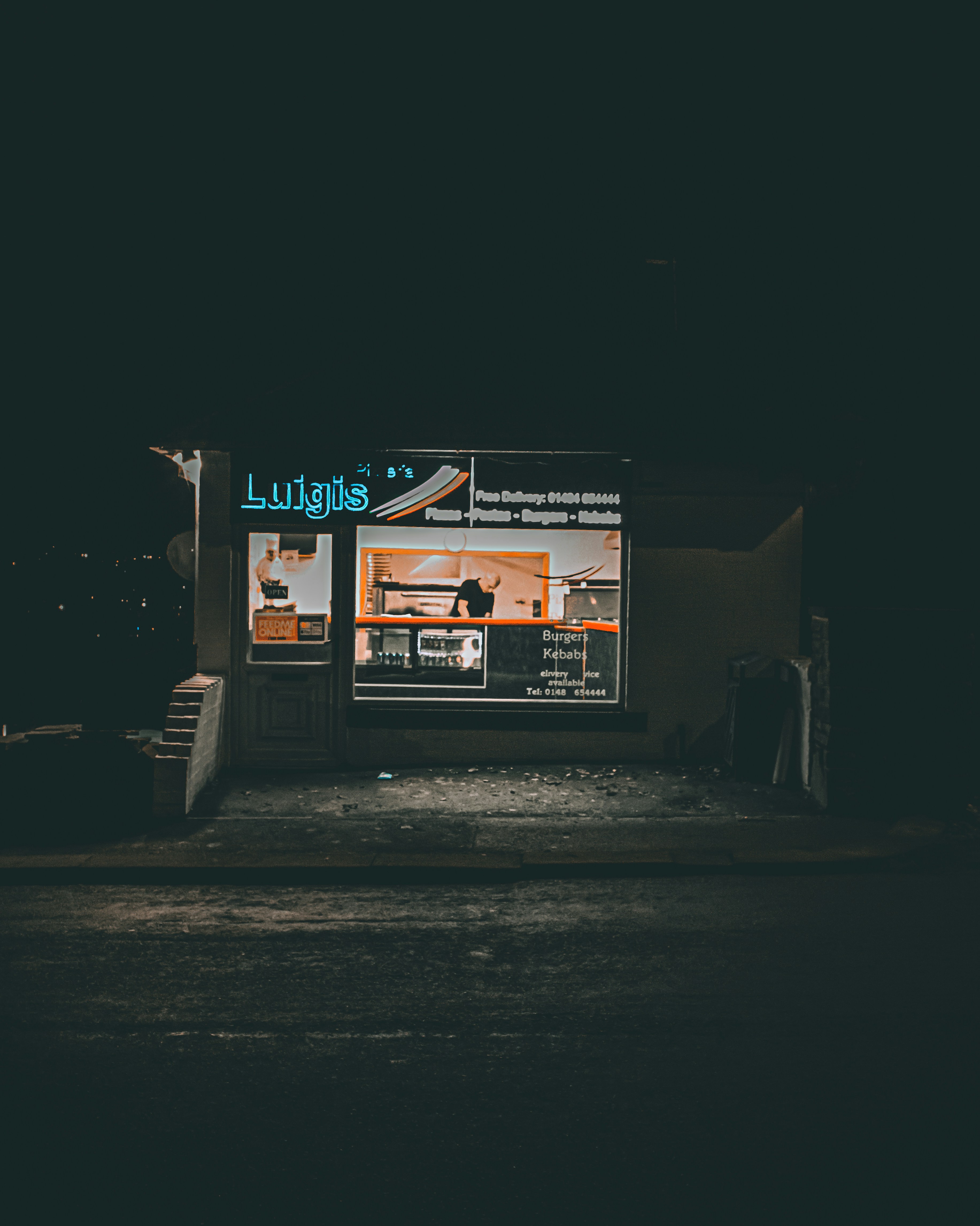 A dark street at night with a store front lit up