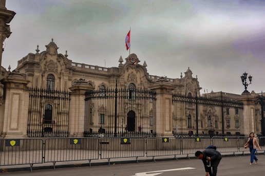 A group of people walking across a street in front of a large building