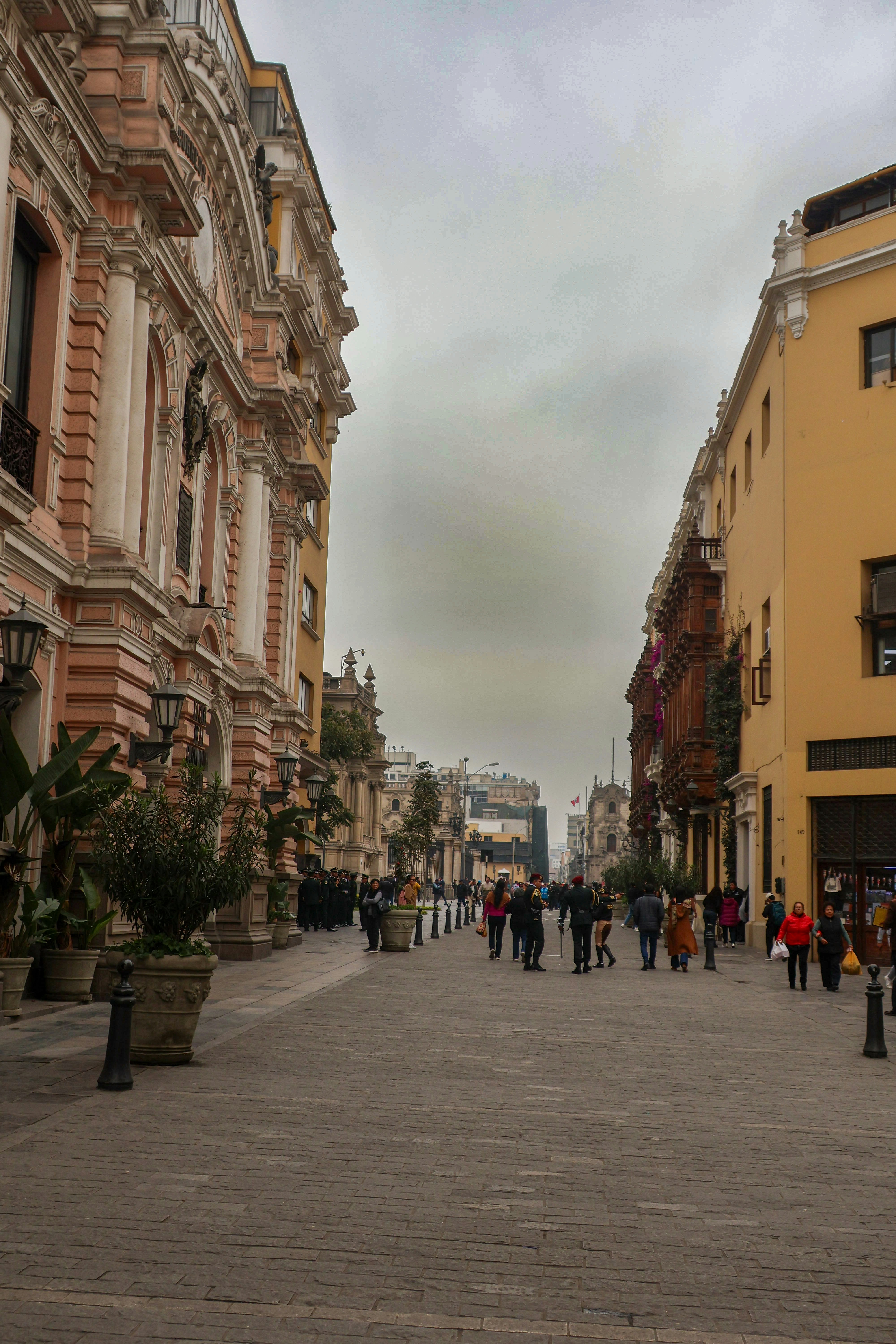 A group of people walking down a street next to tall buildings