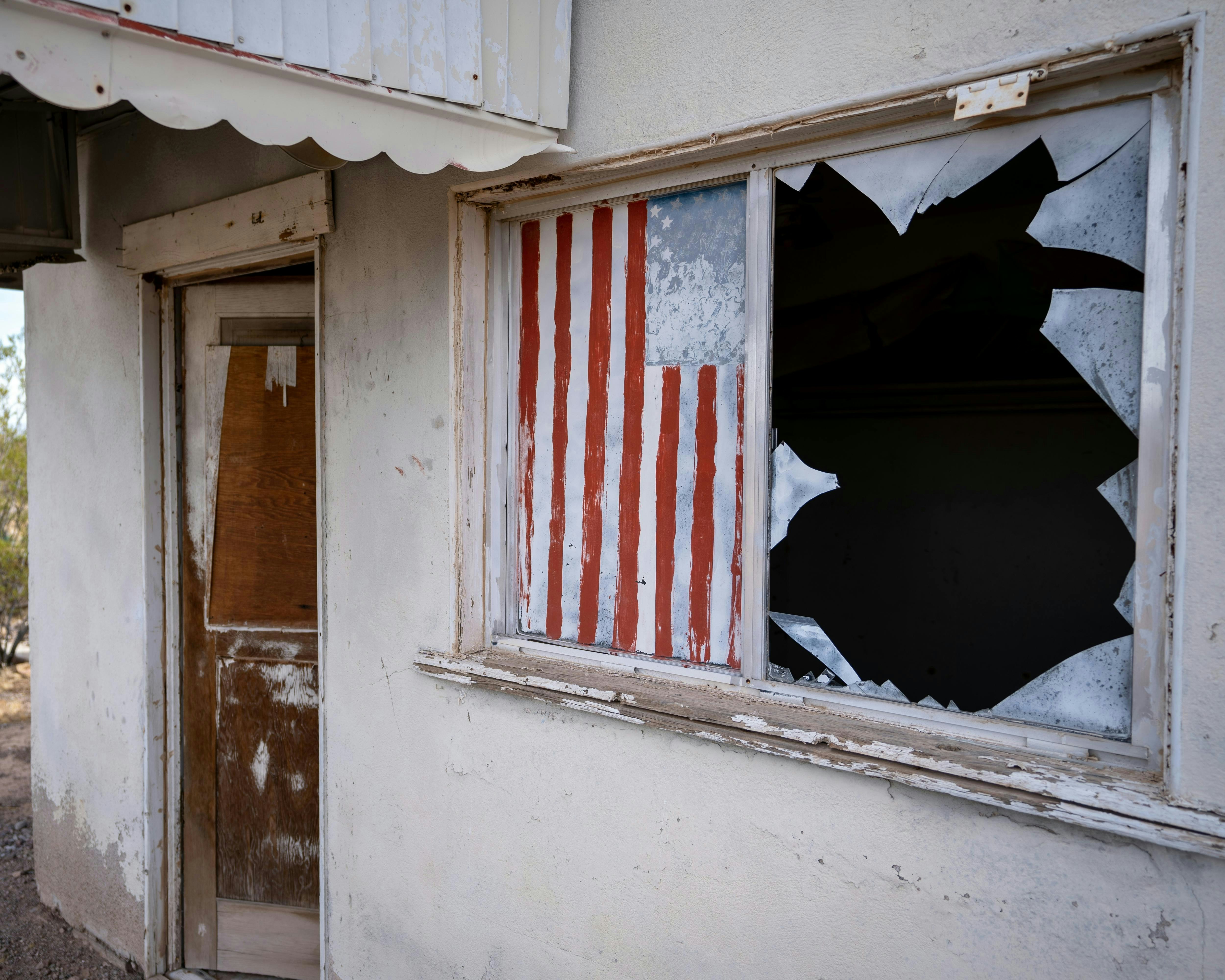An old building with a broken window and american flag on it
