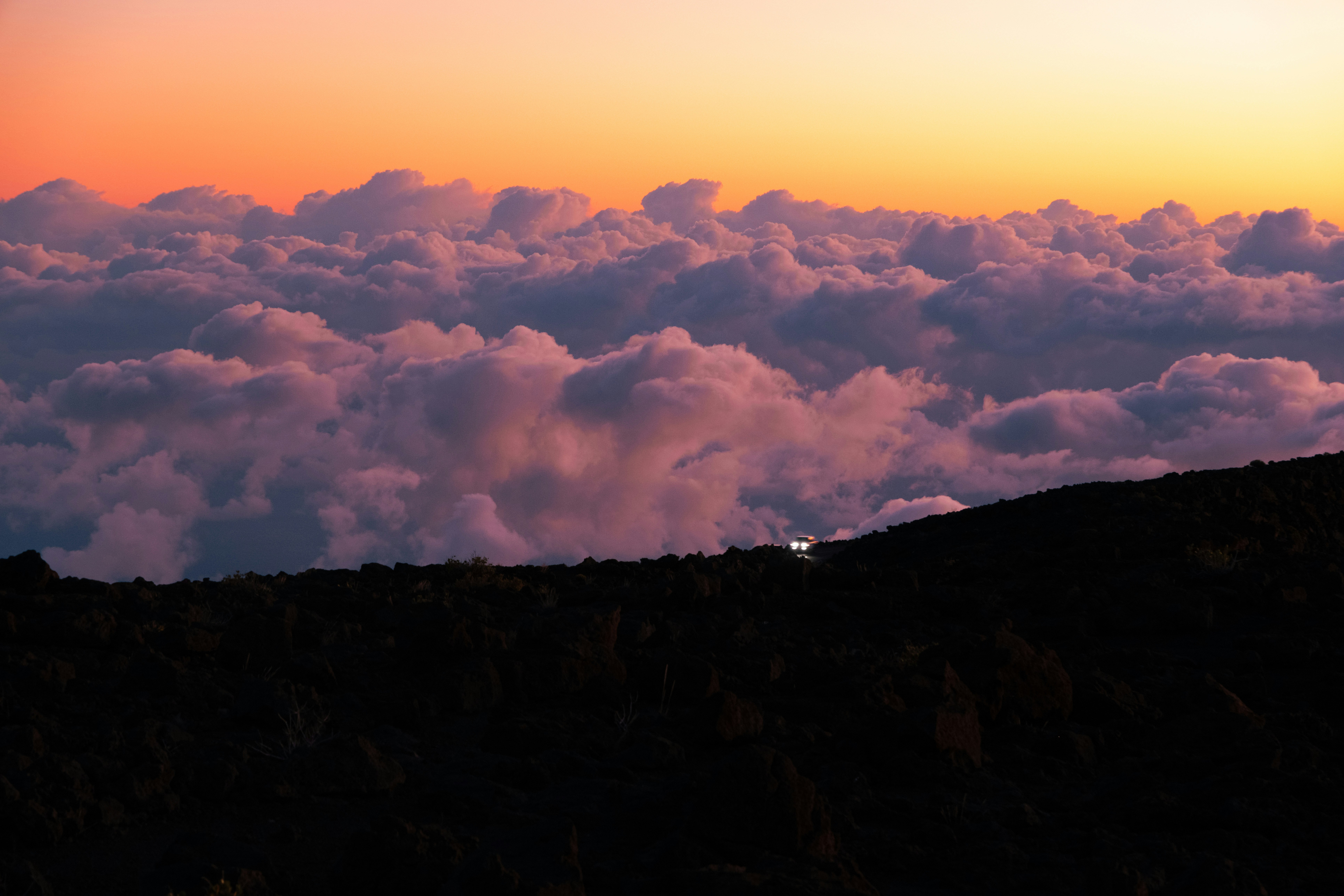 A person standing on top of a mountain with a sky background