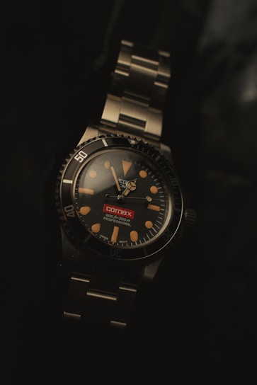 A watch sitting on top of a metal bracelet