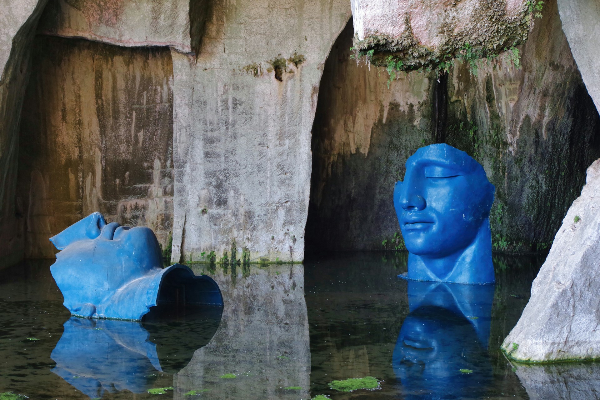 A blue statue is in a pool of water