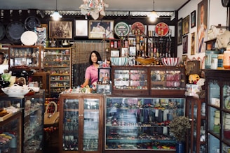 A woman standing in front of a store filled with items