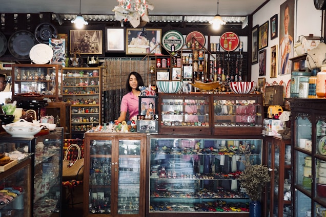 A woman standing in front of a store filled with items