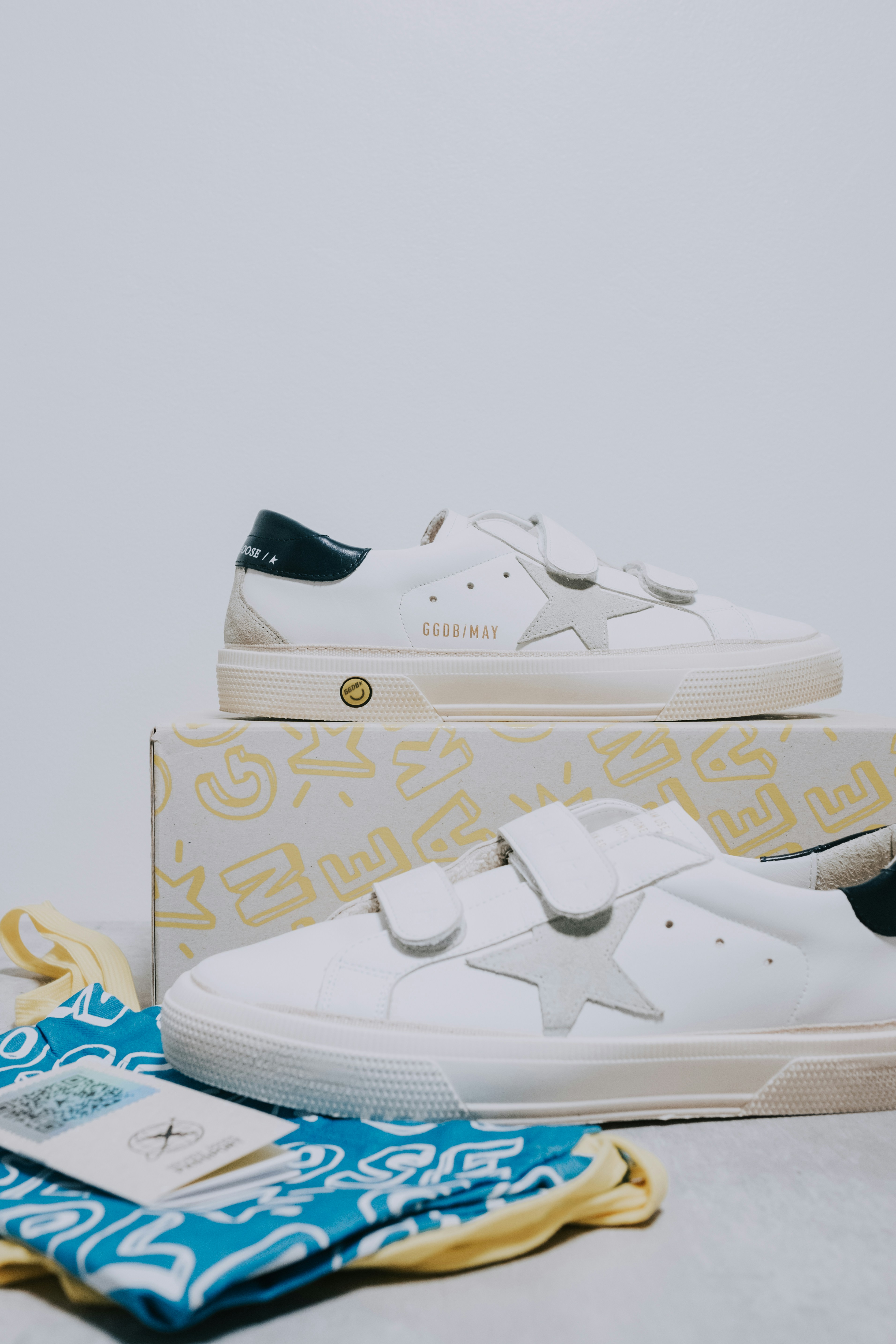 A pair of white sneakers and a blue and yellow towel