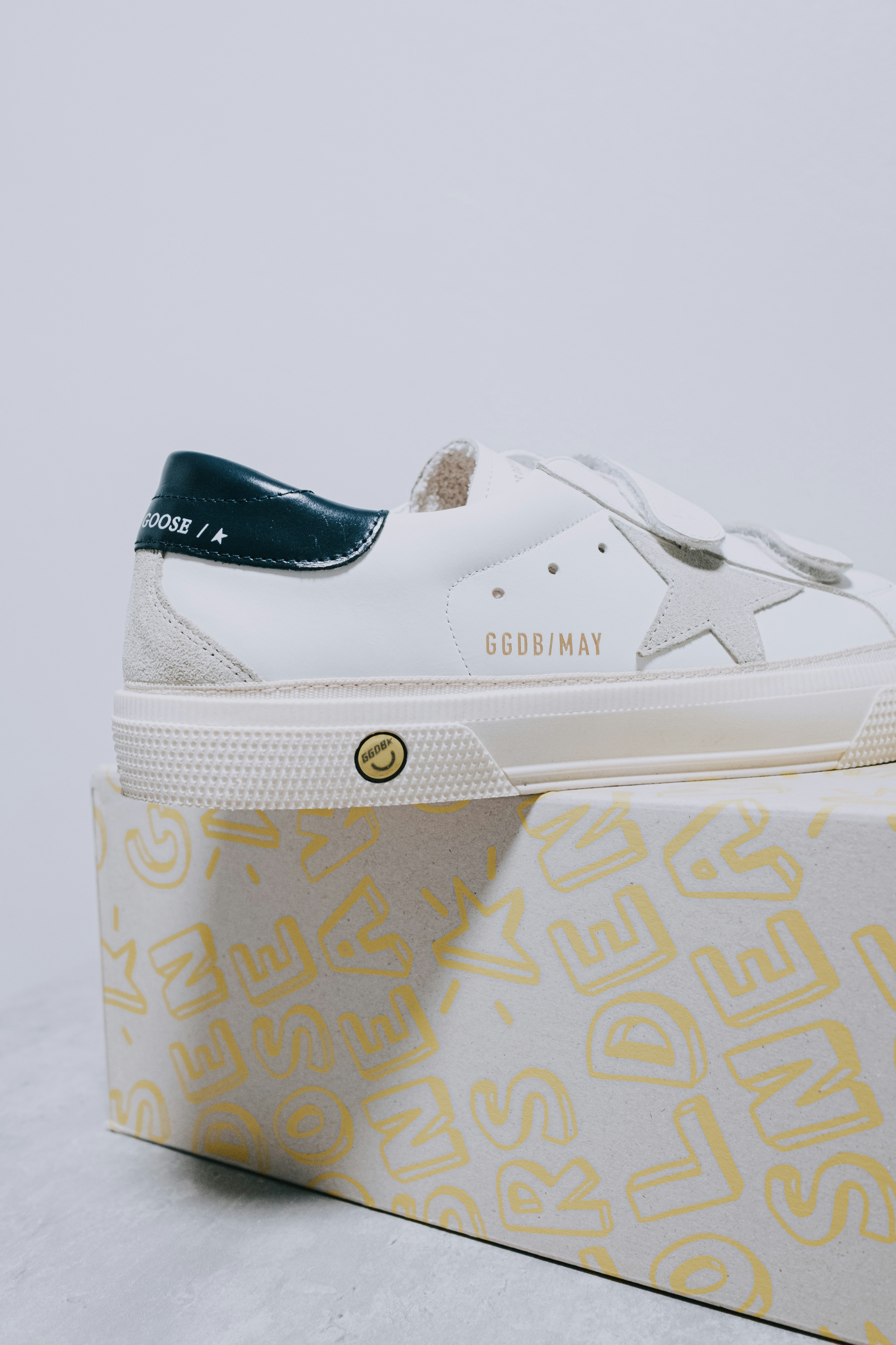 A white sneaker with a blue and yellow sole