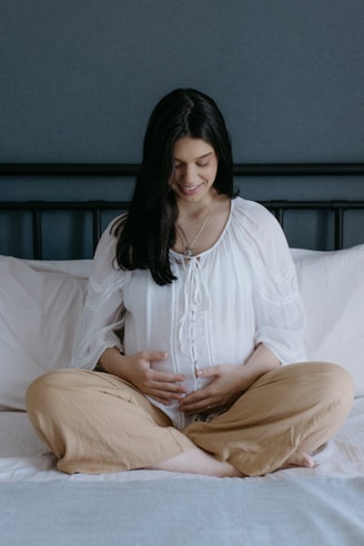 A pregnant woman is sitting on a bed