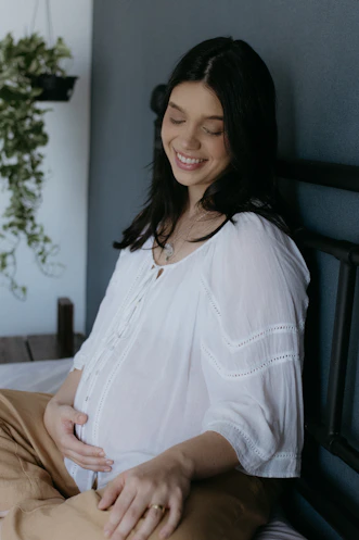 A woman sitting on a bed smiling at the camera