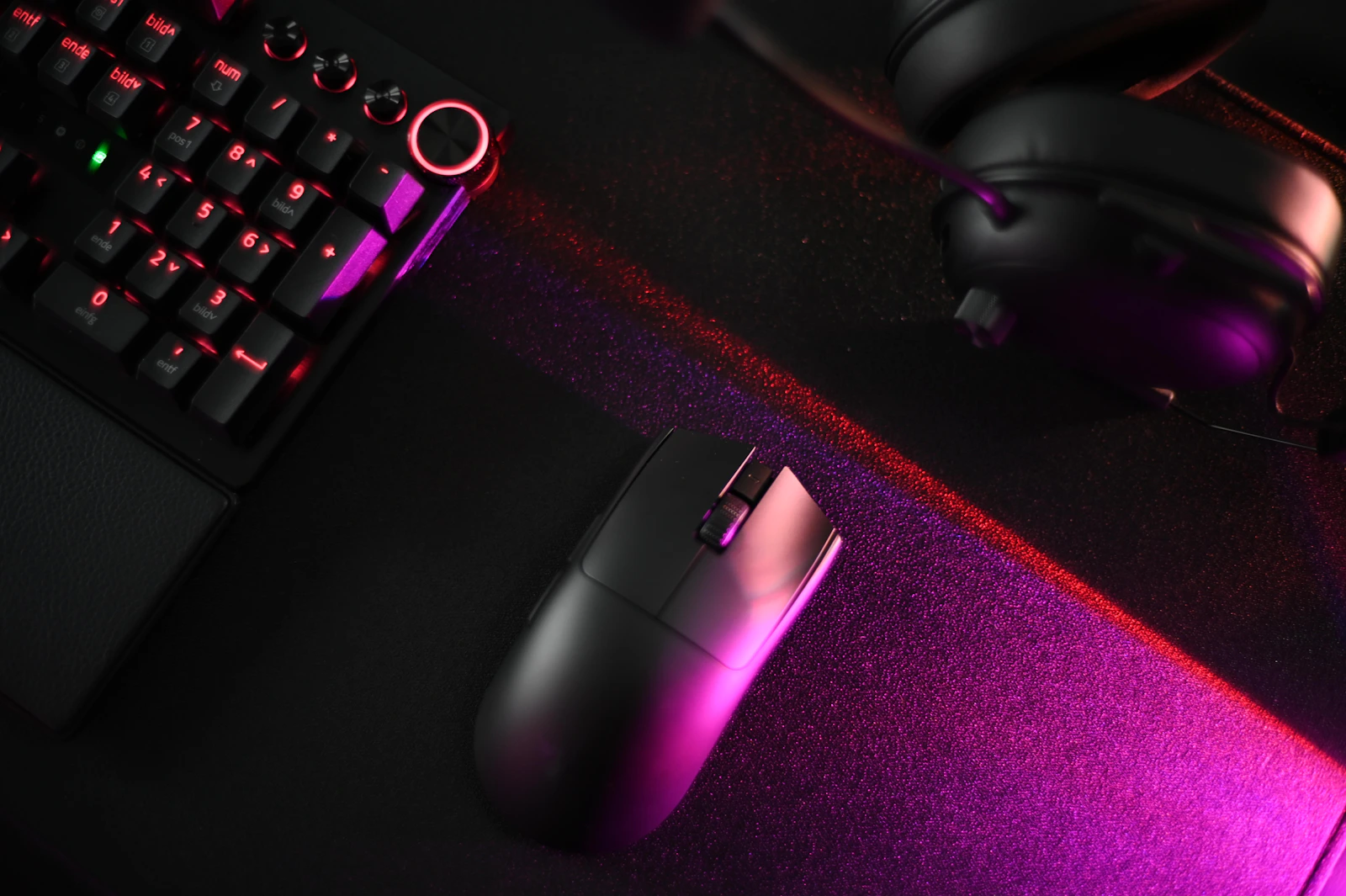Gaming keyboard, mouse, and headset illuminated by red and purple light