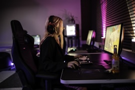A woman sitting in front of a computer with headphones on