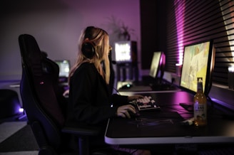 A woman sitting in front of a computer with headphones on