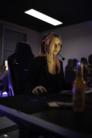 A woman sitting at a desk with a bottle of beer