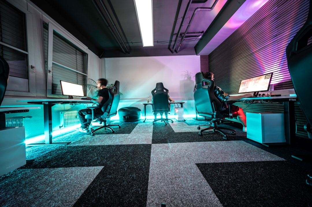 A group of people sitting around a computer desk, 1337Camp offers a unique environment perfectly tailored to the needs of gamers and creatives. Our facility features customizable lighting and LED floor lights that change colors to create the ideal atmosphere. The dojo-like design of the camp promotes a balance of relaxation and focus, allowing you to actively unwind while staying driven towards your goals. At 1337Camp, technology and design come together to create an inspiring and productive space that empowers you to reach your full potential.