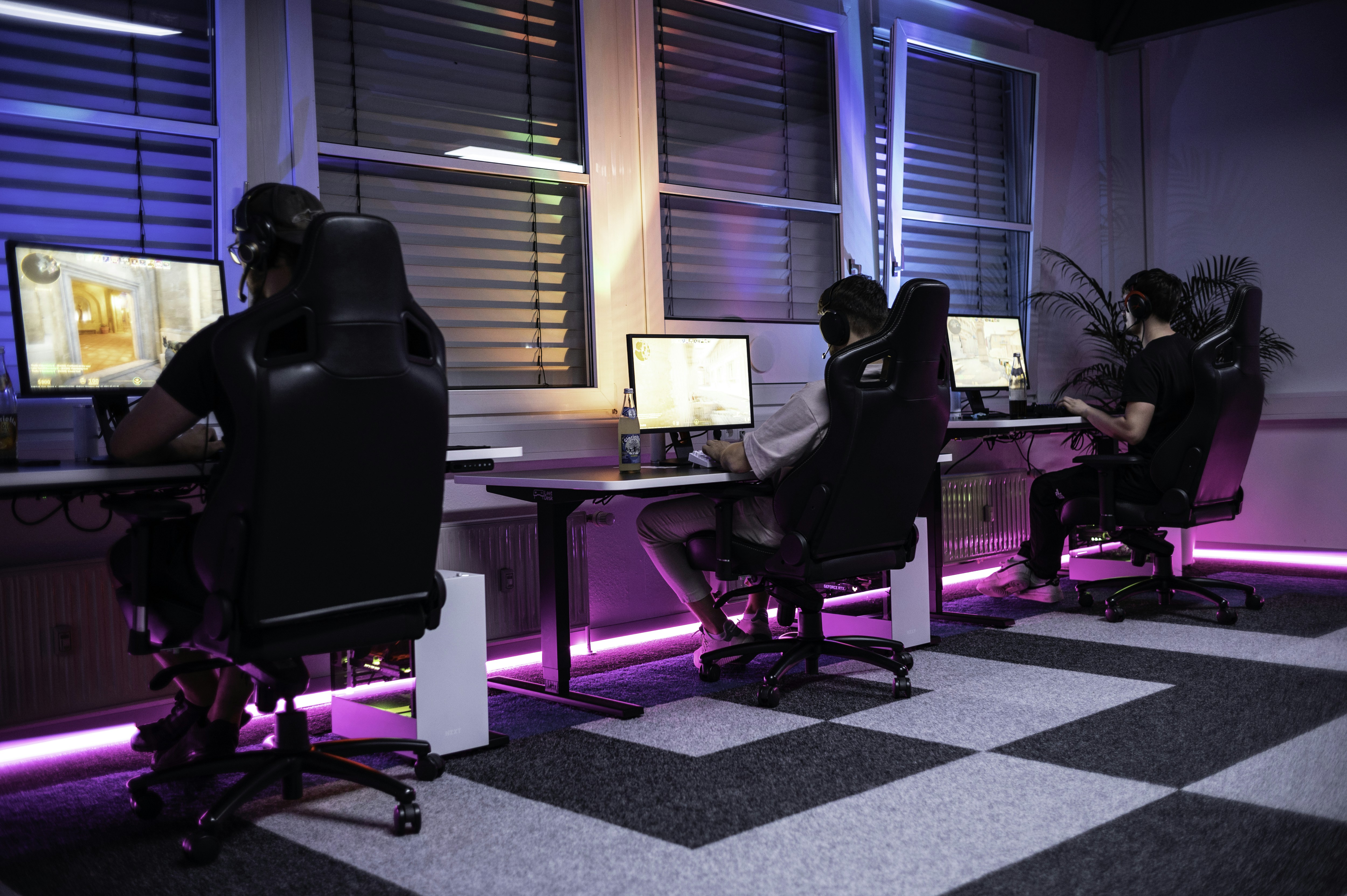 A group of people sitting at computers in a room, 1337Camp offers a unique environment perfectly tailored to the needs of gamers and creatives. Our facility features customizable lighting and LED floor lights that change colors to create the ideal atmosphere. The dojo-like design of the camp promotes a balance of relaxation and focus, allowing you to actively unwind while staying driven towards your goals. At 1337Camp, technology and design come together to create an inspiring and productive space that empowers you to reach your full potential.