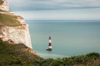 A red and white lighthouse sitting on top of a cliff